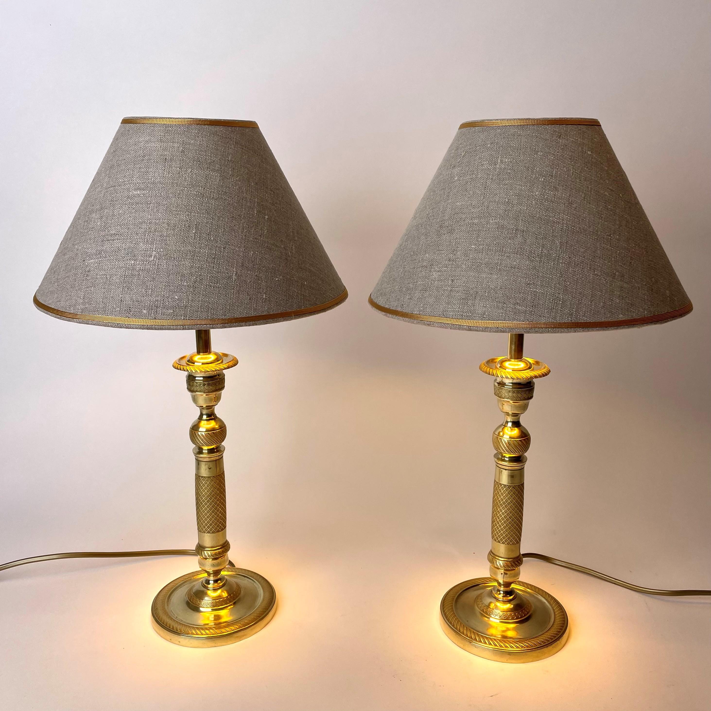 A beautiful pair of table lamps, originally Empire candlesticks in bronze. Made in France in the 1820s and later converted to table lamps in the 20th century.

The lampshades in linen with a gilded inside to give a cozy shine.

Newly installed