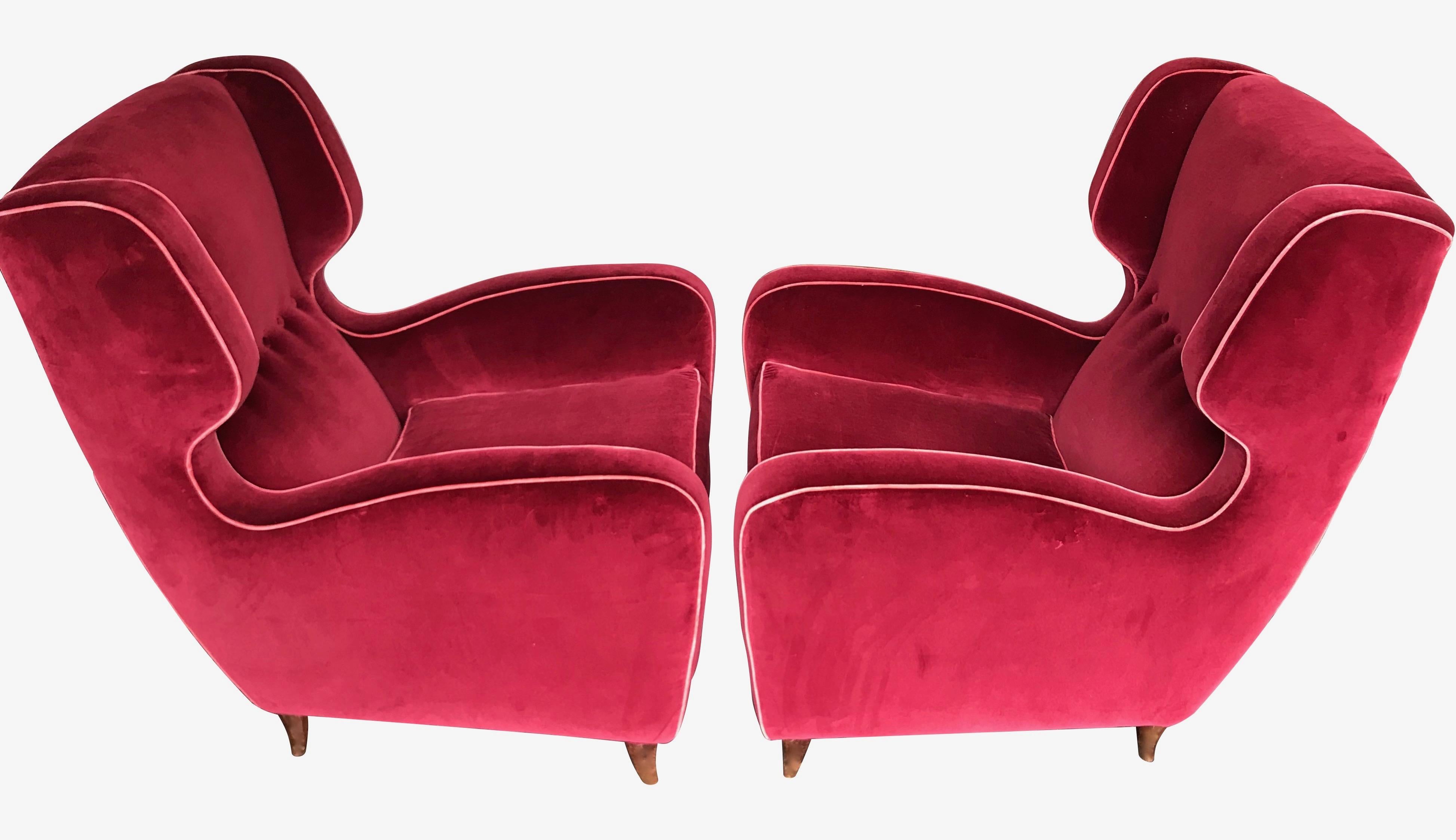 A beautiful pair of wing backed armchairs attributed to Guglielmo Ulrich with original rosewood shaped feet. Upholstered in red velvet with pink piping edging and buttoned back. Stunning design and very comfortable armchairs.