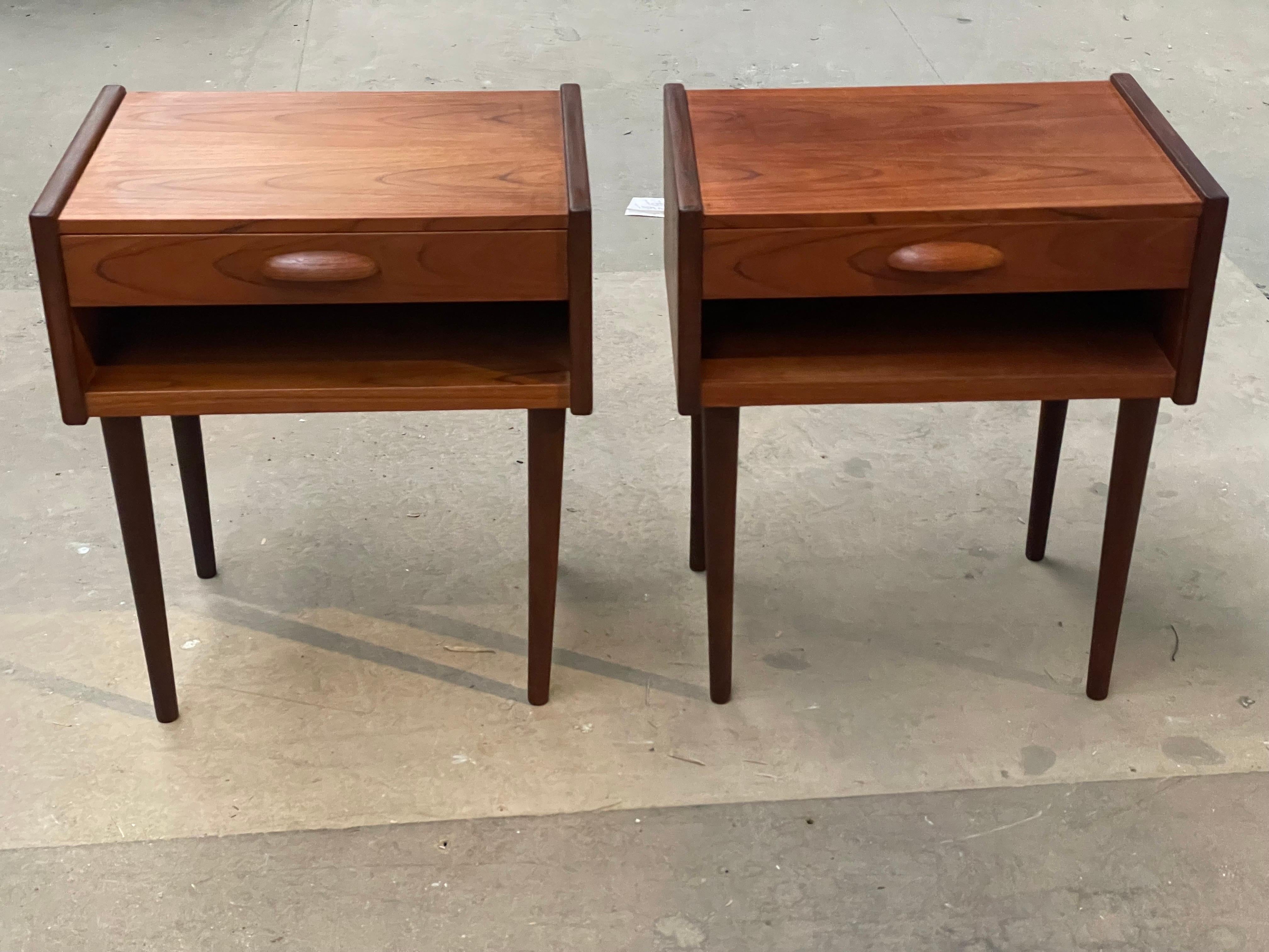 Pair of mid-century Danish teak nightstands, each equipped with a practical drawer and a lower shelf for added storage. The nightstands showcase elegant carved handles, enhancing their minimalist design. Crafted from durable teak wood, these pieces