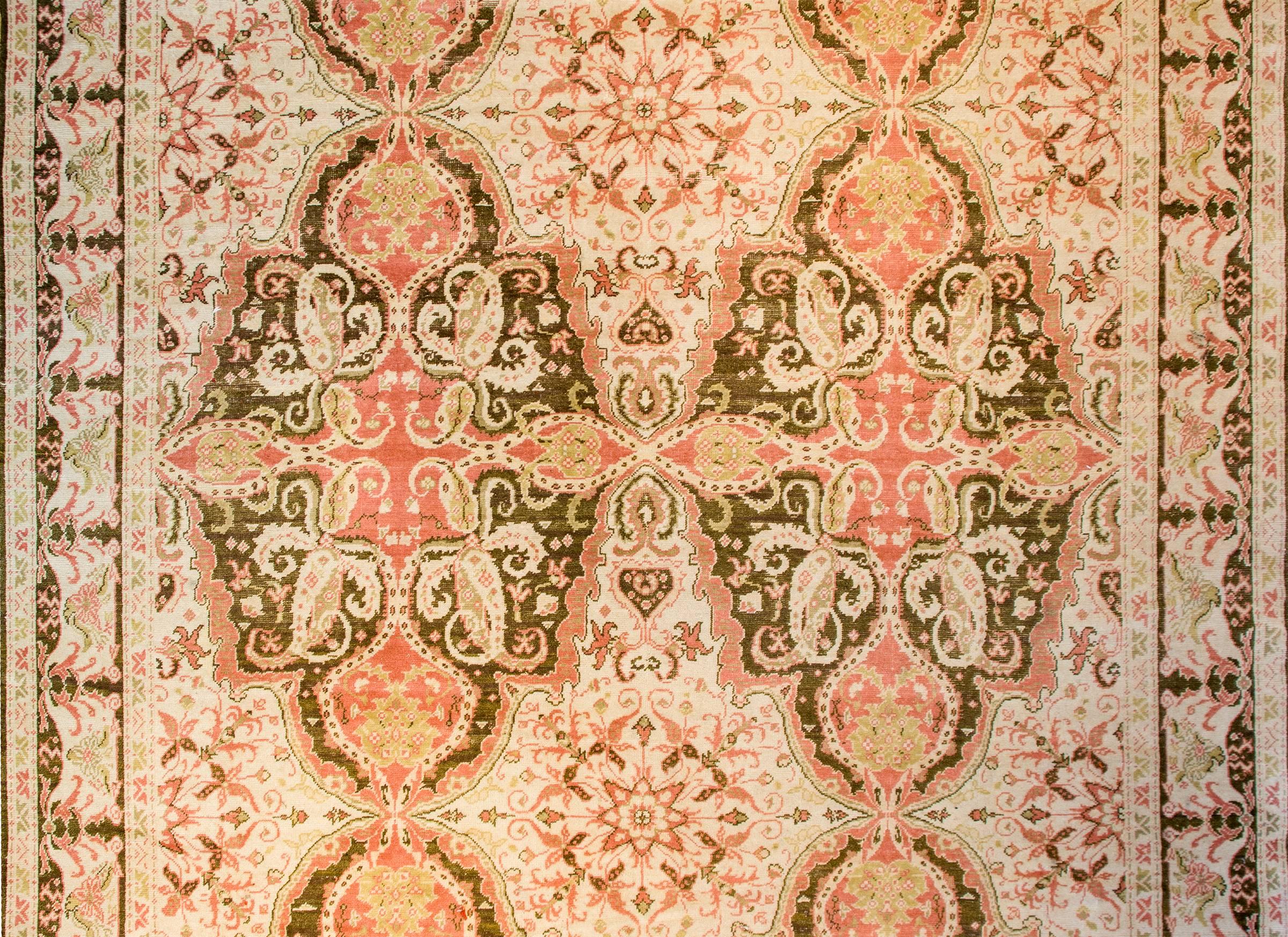 A mesmerizing early 20th century Turkish Keysari rug with an extraordinary pattern of intricately and tightly woven paisley, floral and vines, woven in pink, green, brown, mirrored four ways, on a natural colored wool background. The border is