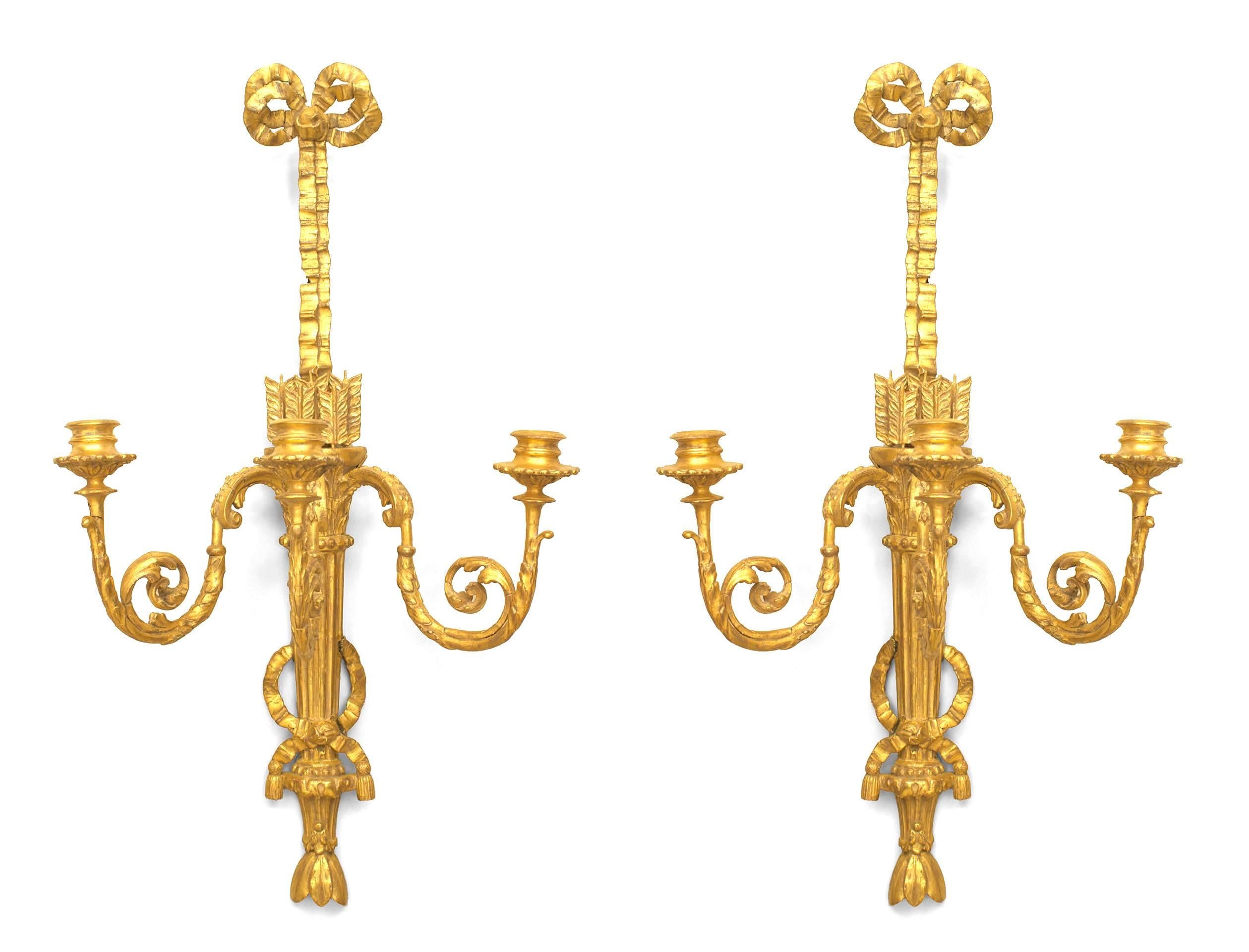 Coppia di appliques francesi Luigi XVI (circa 1785) in legno dorato a tre bracci a voluta con un nodo a fiocco sulla parte superiore e un disegno con frecce in una faretra. (PREZZO A COPPIA)
