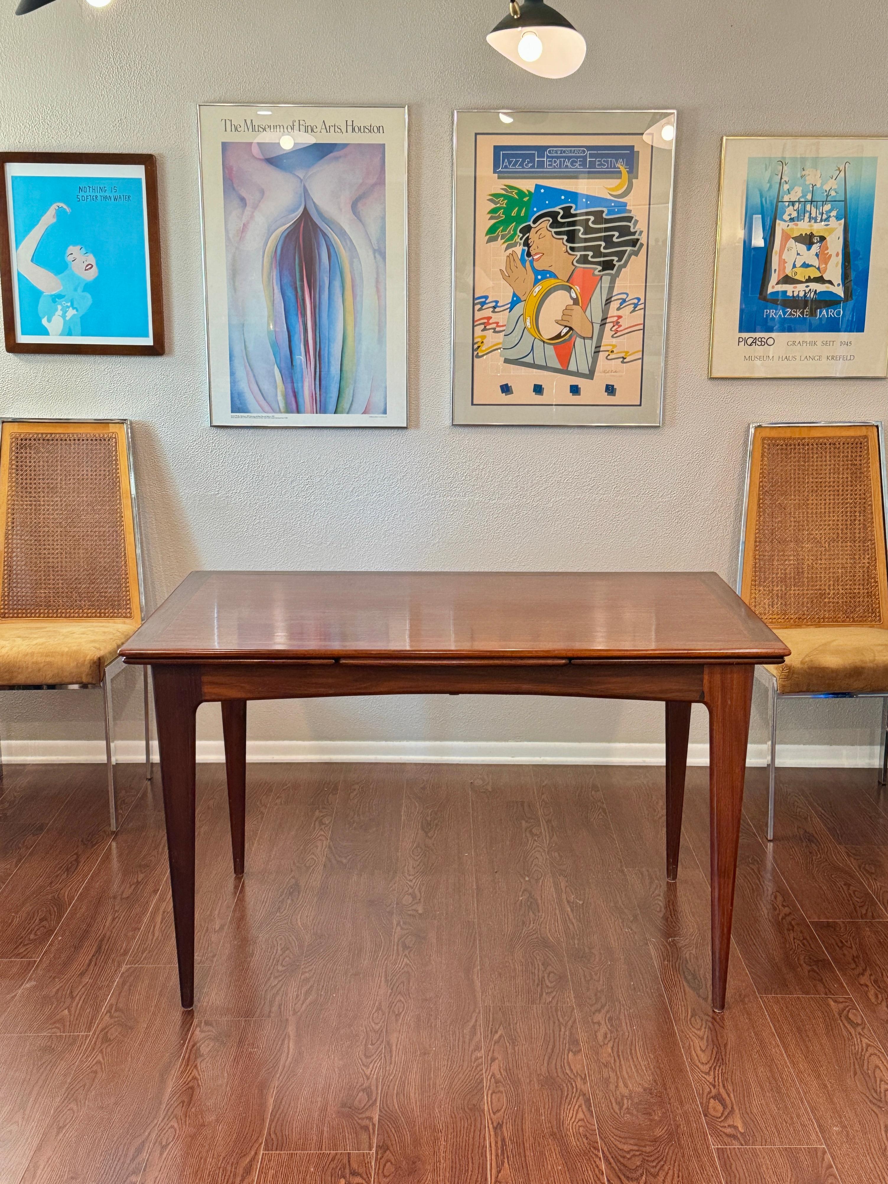 A beautifully designed extending draw leaf dining table designed by John Herbert for Younger, circa 1960s. In a dark afromosia teak with a sculptural base. In good overall condition with some wear on the surface like scratches. Structurally sound