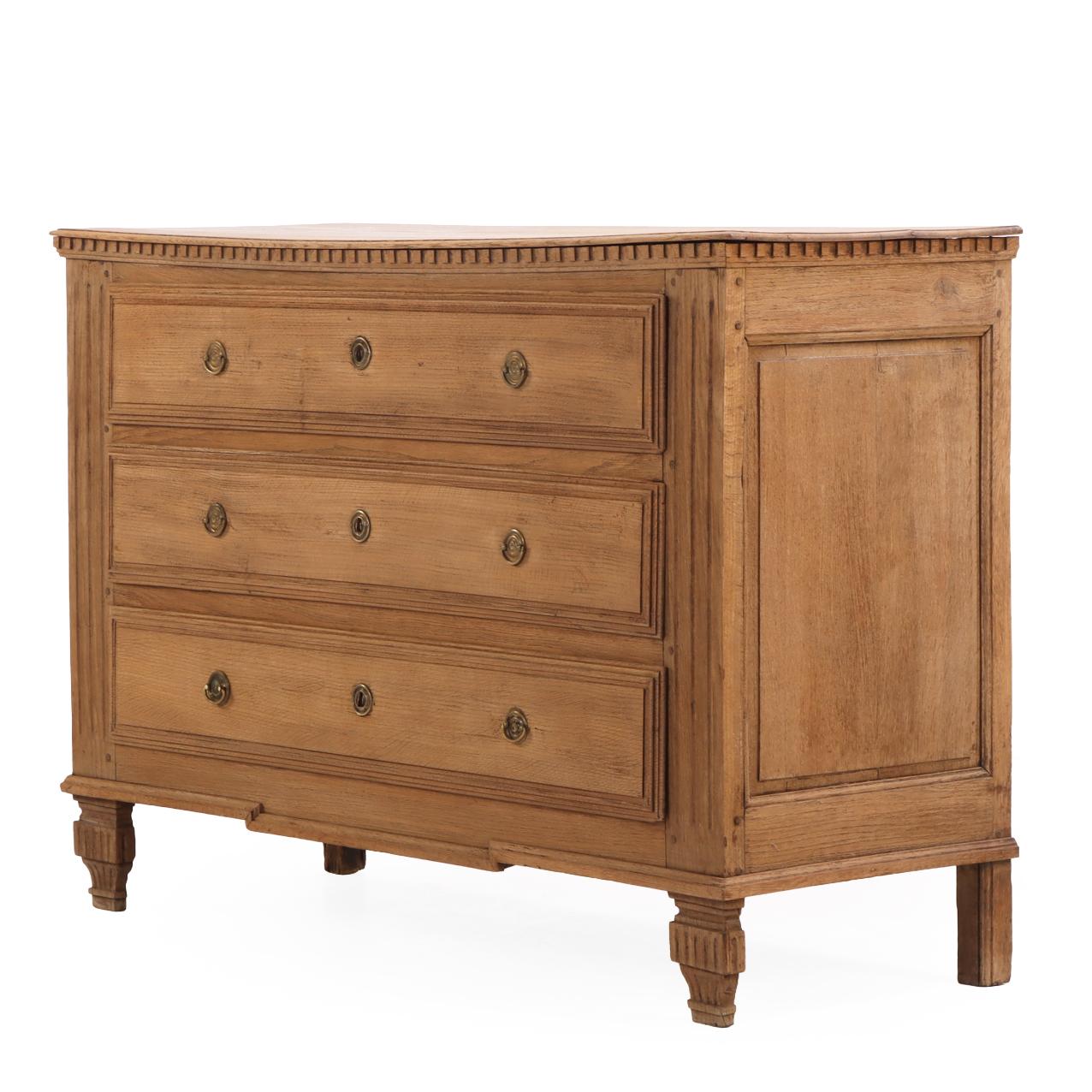 A handsome mid-19th-century Belgian oak commode featuring top with dentil molded detail above three full-width drawers framed with stepped molding and brass ring pulls. The case rests on wonderfully detailed, carved front feet that lend a refined