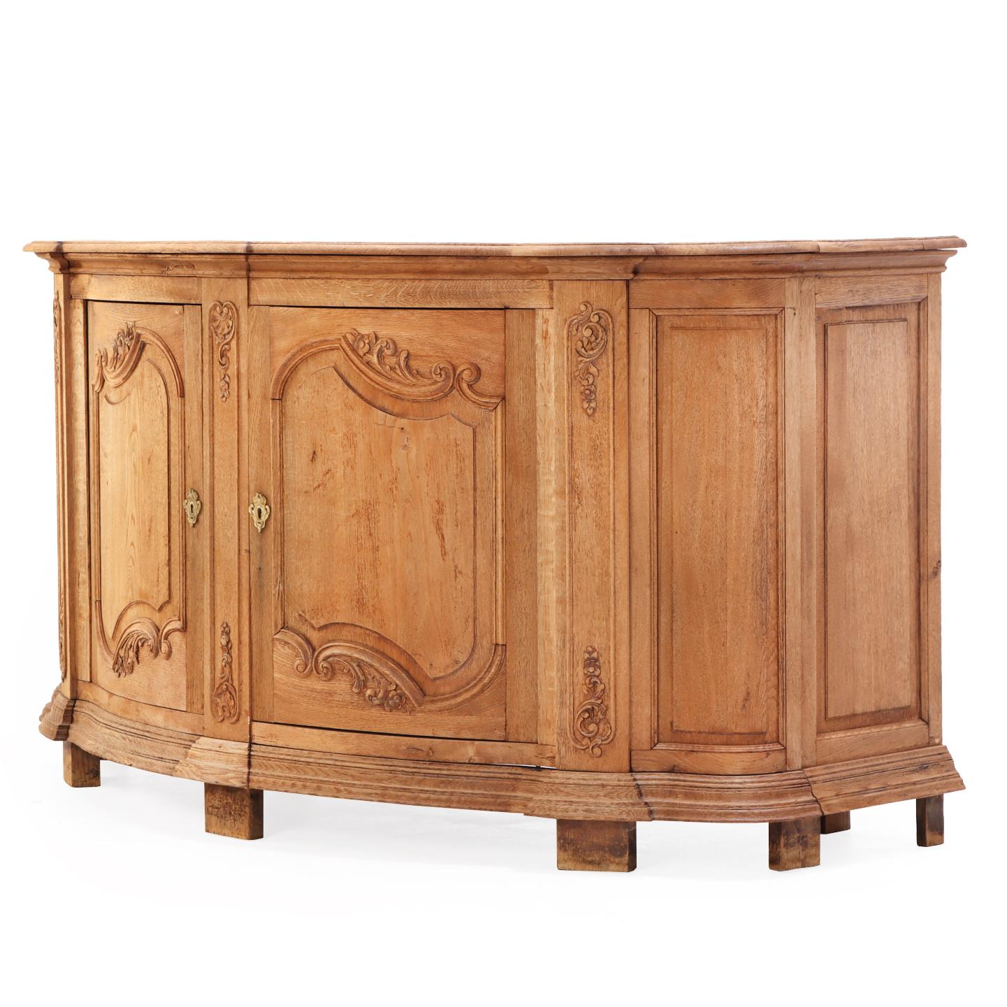 The deep, bowfront case is constructed with two carved, paneled doors, flanked carved style, all resting on a molded base with short plain feet. This piece has wonderful carved embellishments on the case with ample storage and ready to be enjoyed in