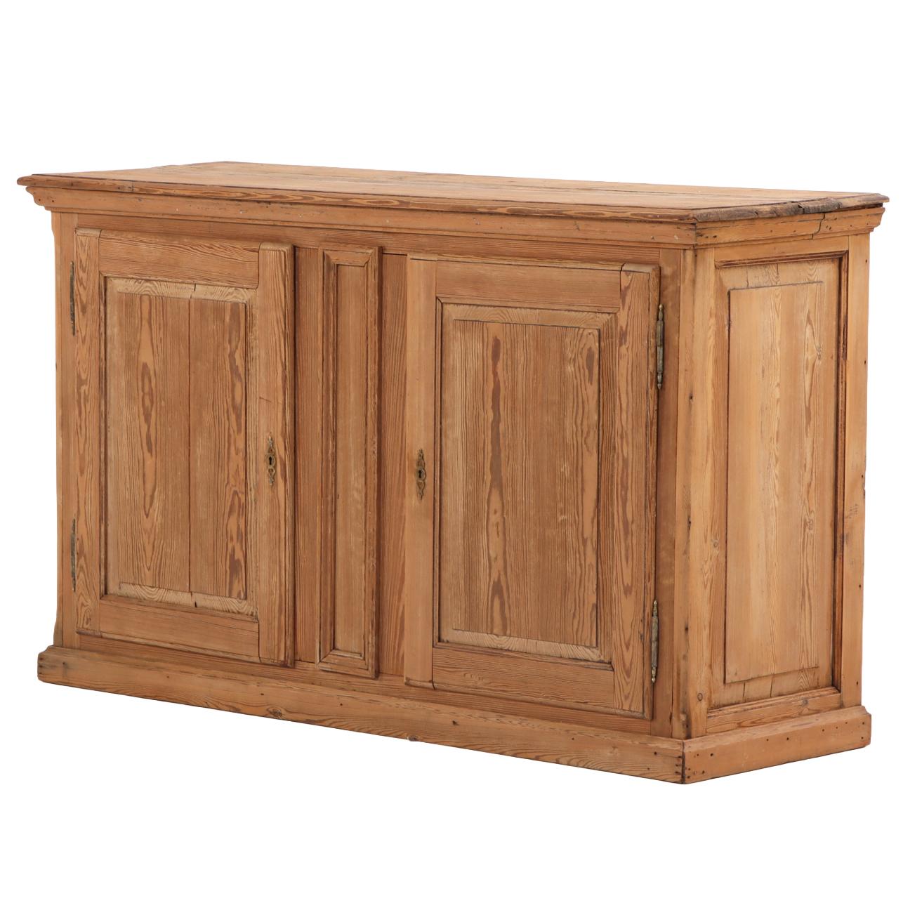 A handsome 19th-century server featuring a molded top and matching molded base. The façade presents two paneled doors flanking a central carved stile, opening to an interior fitted with shelves for practical storage. Warm patina, clean lines, and