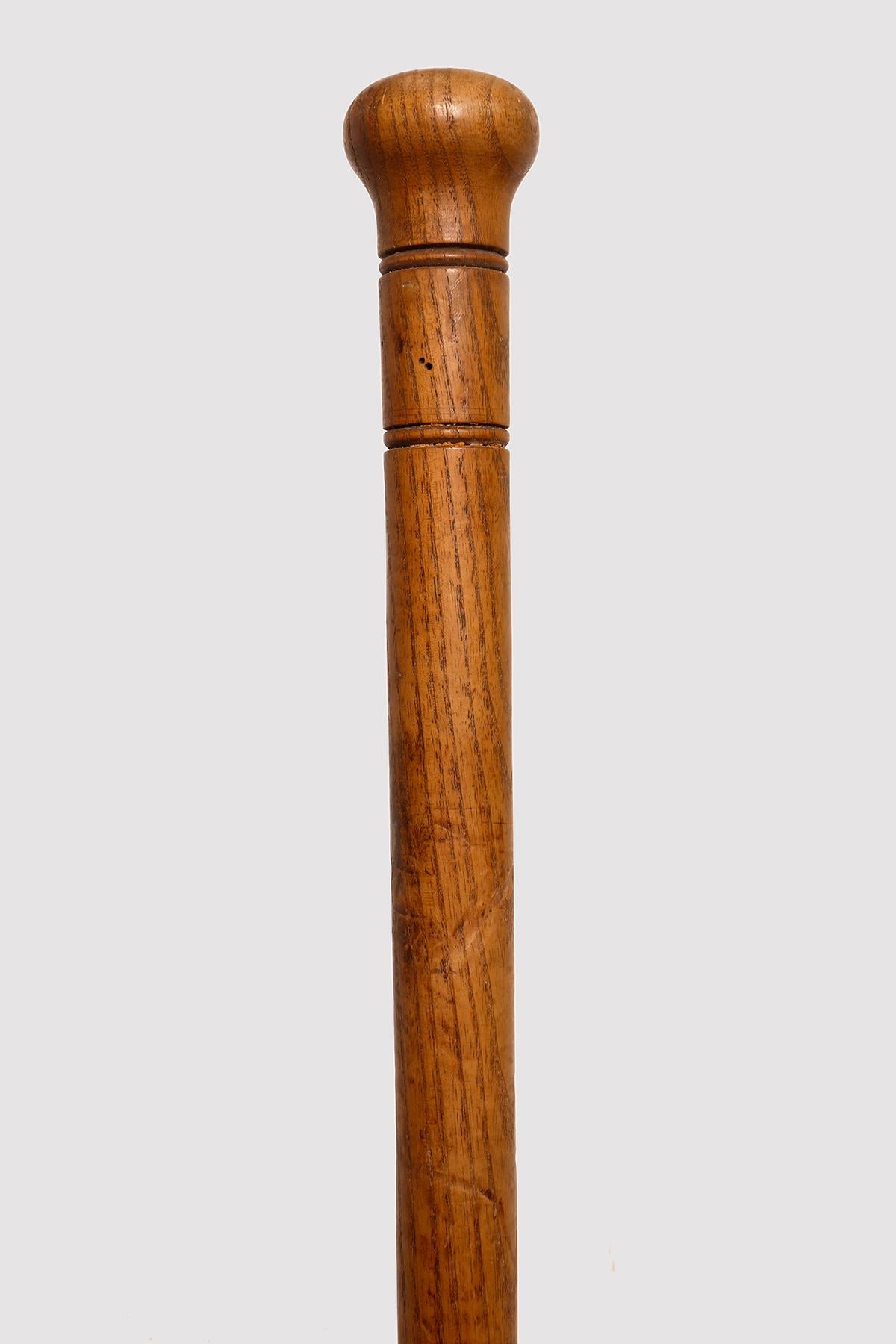System walking stick. A Belgian walking stick to be used by a postman. The stick and the pommel are obtained from a single fruit branch. The milord pommel is decorated towards the shaft by two pairs of engraved circles. The ferrule is made of iron