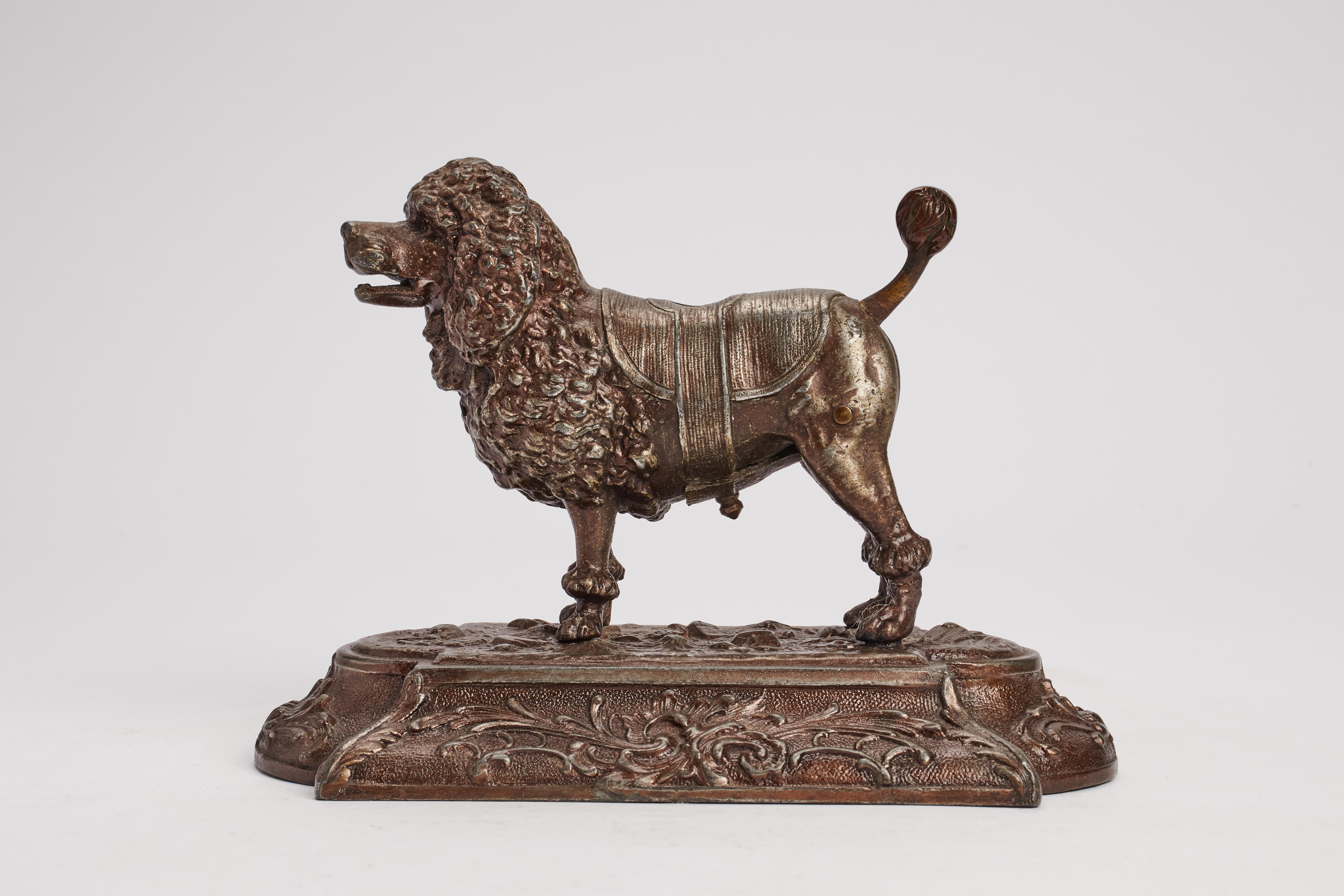 White metal sculpture on a rectangular base depicting a poodle dog acting as a cigar cutter. Signed DRG Musterschutz. Austria around 1890.