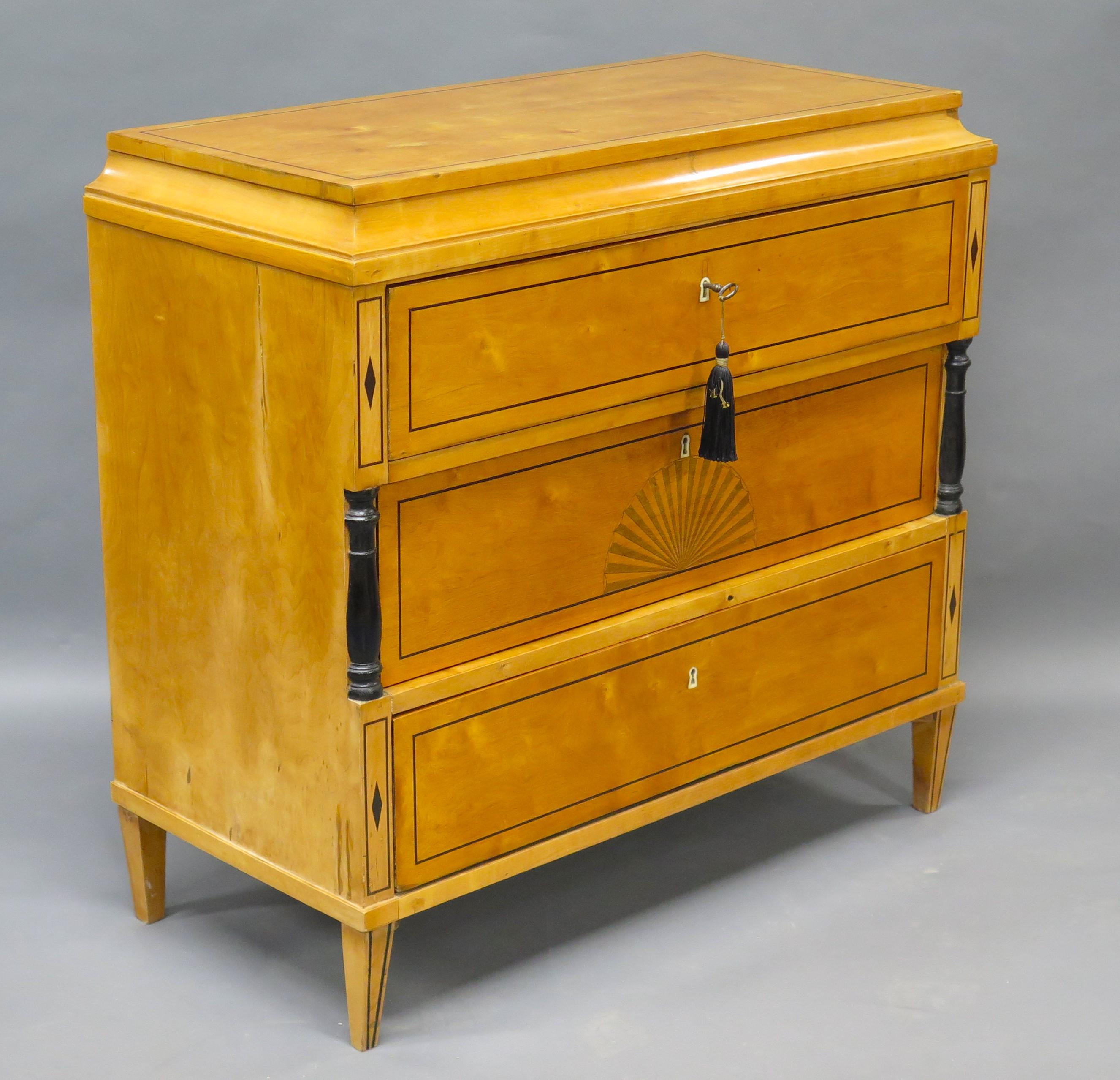 a biedermeier inlaid commode first half 19th century the recessed top over three inlaid long drawers, top and bottom drawers with twin daimonds inlaid daimonds stiles the center drawers with center inlaid fan medallion flanked by ebonyed stiles at