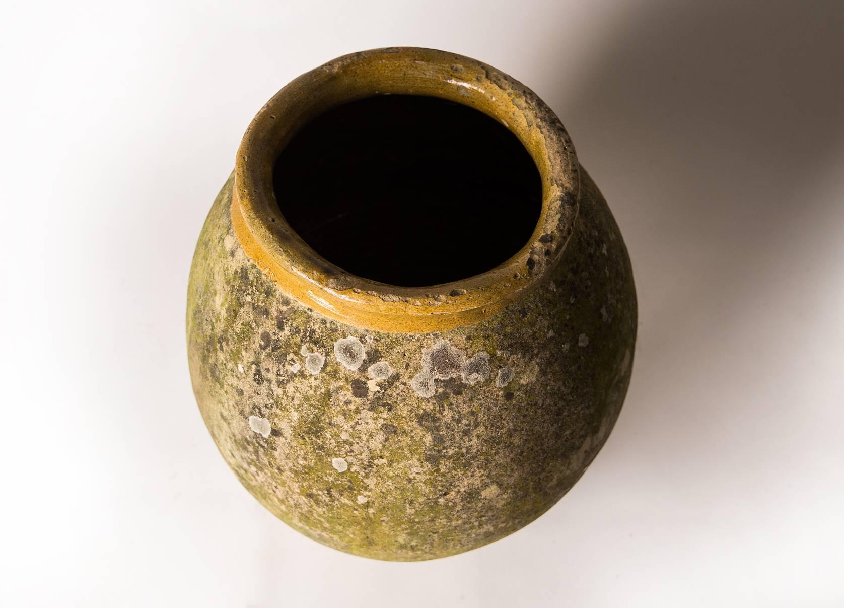 An oilve oil jar from the Biot, Alpes-Maritimes region known as a pottery centre from the 18th century onward. Featuring an ochre glazed rim over a smooth, cylindrical body with incredible ageing/patination with an ochre hue. Functional as a