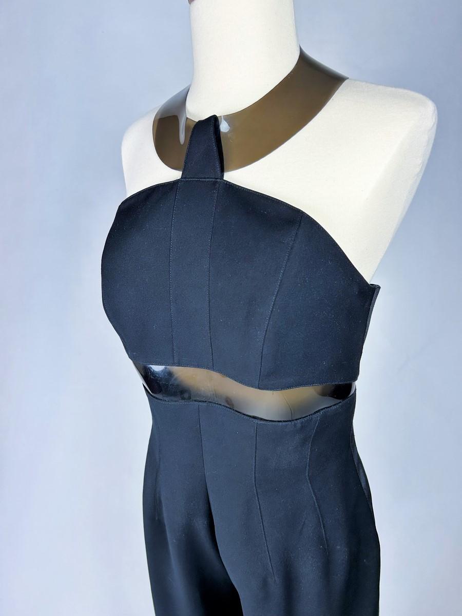 Circa 1995-2000

France

Elegant evening jumpsuit in stretch polyester by Thierry Mugler dating from 1995-2000. Slim-fitting suit, large halter neckline with transparent and smoked vinyl hoop and under-bust detail, a nod to 1970s modernism. Fitted