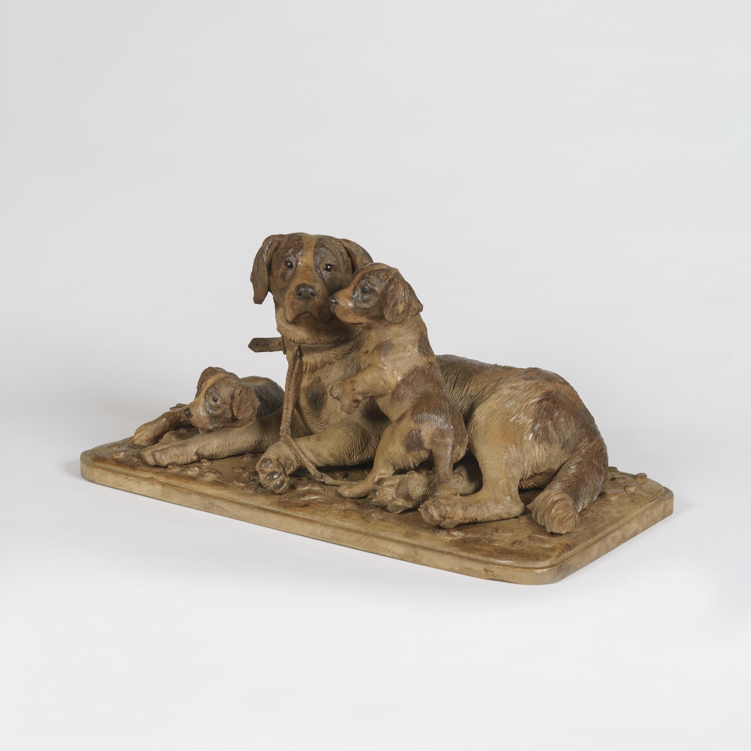 Groupe de chiens sculptés de la Forêt-Noire
Construite en bois de tilleul sculpté et teinté de manière naturaliste, sur une base rectangulaire aux angles arrondis, la chienne couchant et s'occupant de ses deux petits, tous munis d'yeux en verre