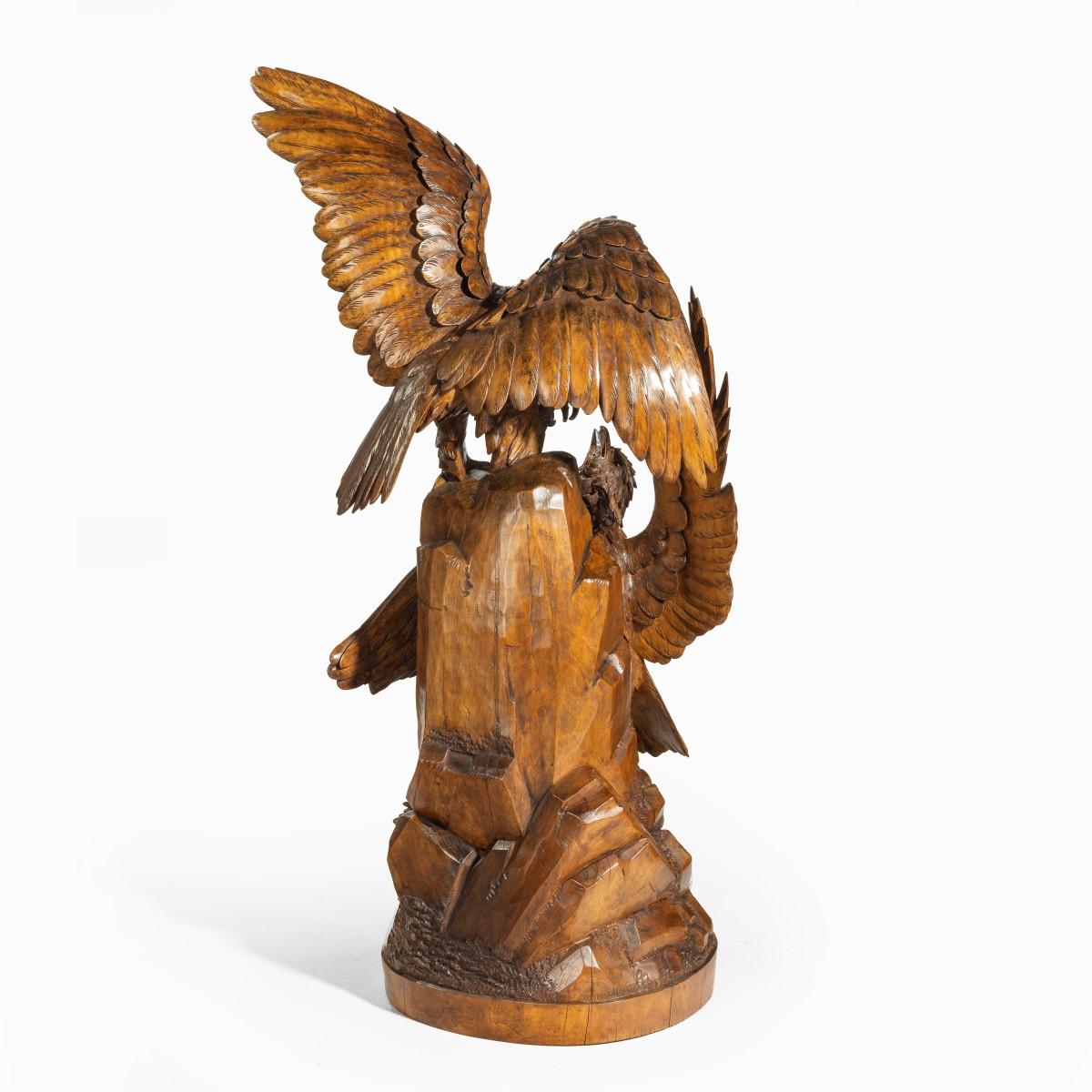 A ‘Black Forest’ carving of two quarrelling golden eagles, the linden wood carving with one bird attempting to displace the other bird from the top of a rocky outcrop, applied with a brass plaque ‘Sculptures Binder, Lucerne, Zermatt, St. Moritz.