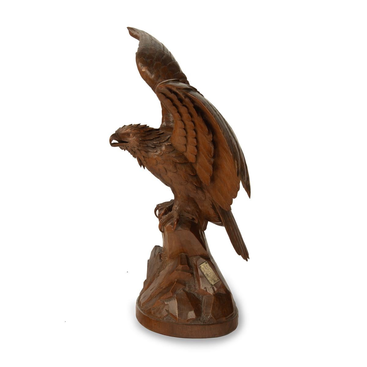A ‘Black Forest’ linden wood eagle, naturalistically carved with wings outstretched, perched on a rocky outcrop, the base with a rubbed metal maker’s plaque most probably for Binder of Lucerne, Zermatt and St. Moritz, made in Brienz.  Swiss, circa