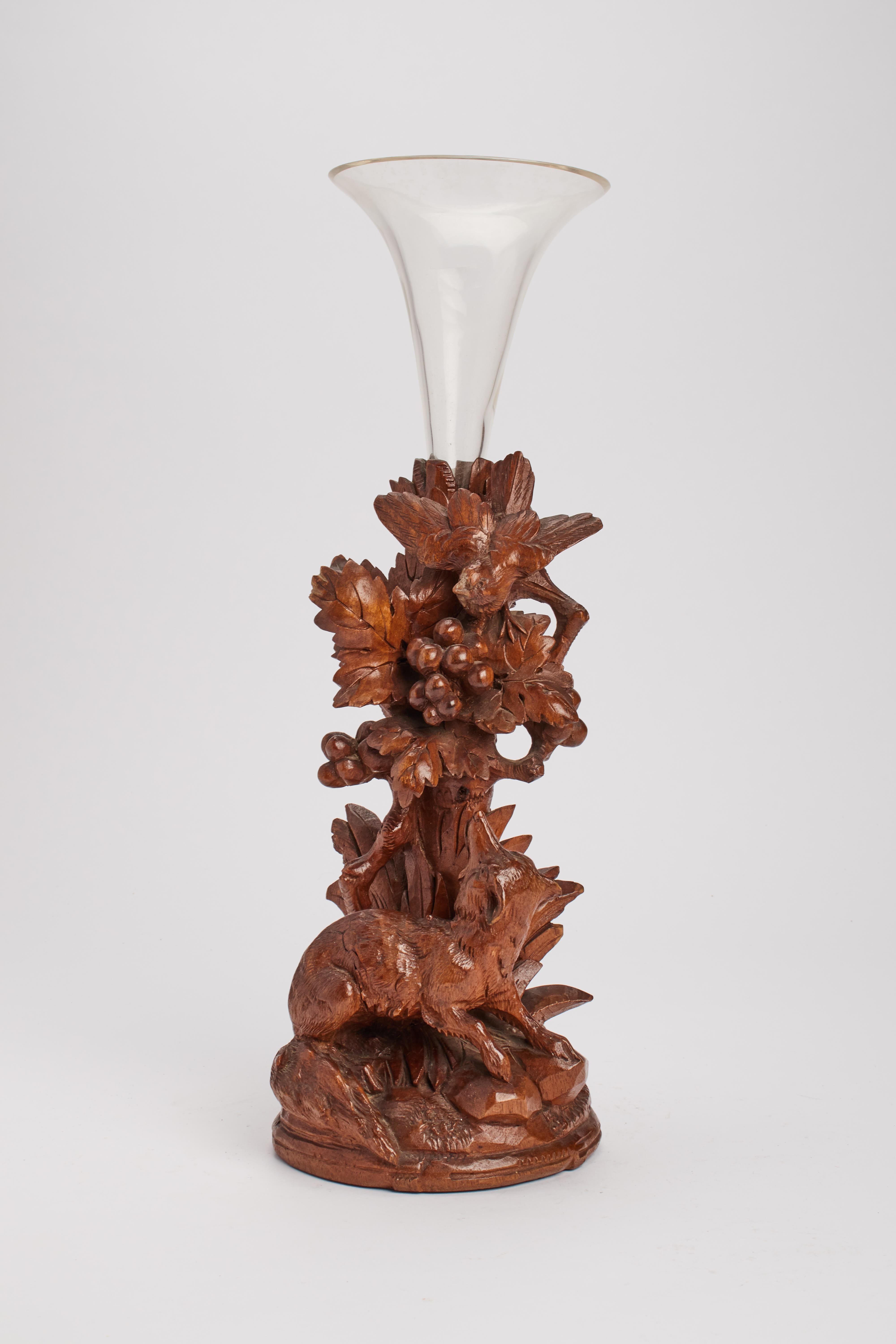 Flower vase realizesd with hazelnut carved wood, depicting a fox watching a bird on a tree. Glass vase. Germany, Black Forest, circa 1880.