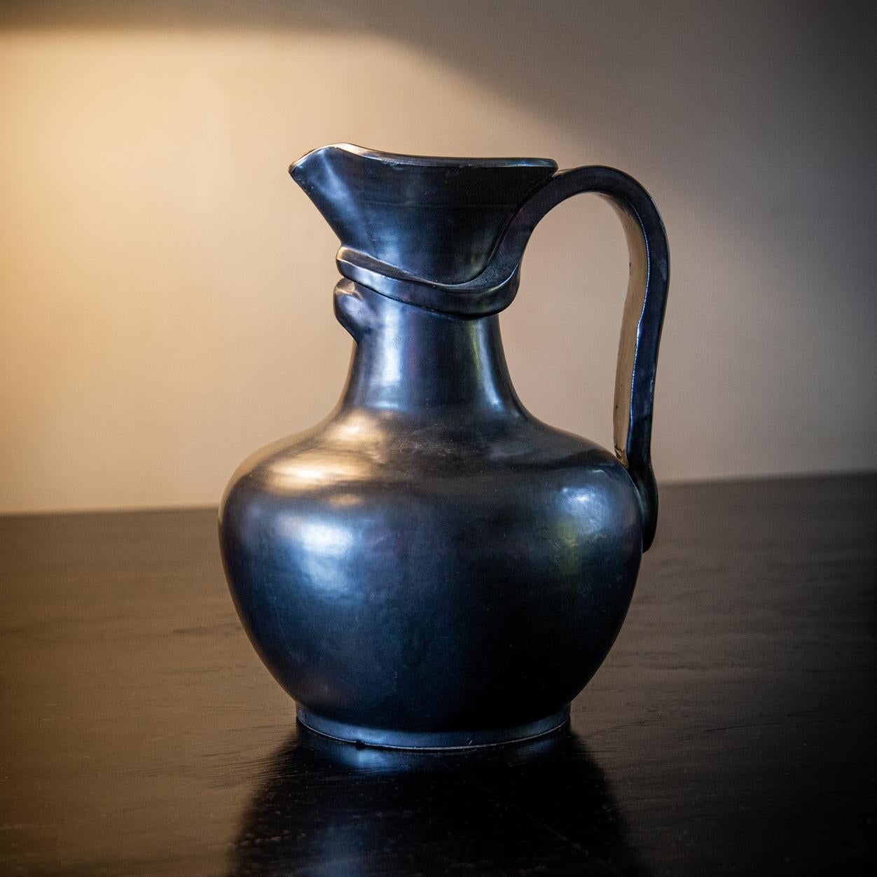Wonderful form and silhouette with looped candle extending around the spout, reminiscent of the work of Georges Jouves. Ideal vintage condition and patina, signed to base.