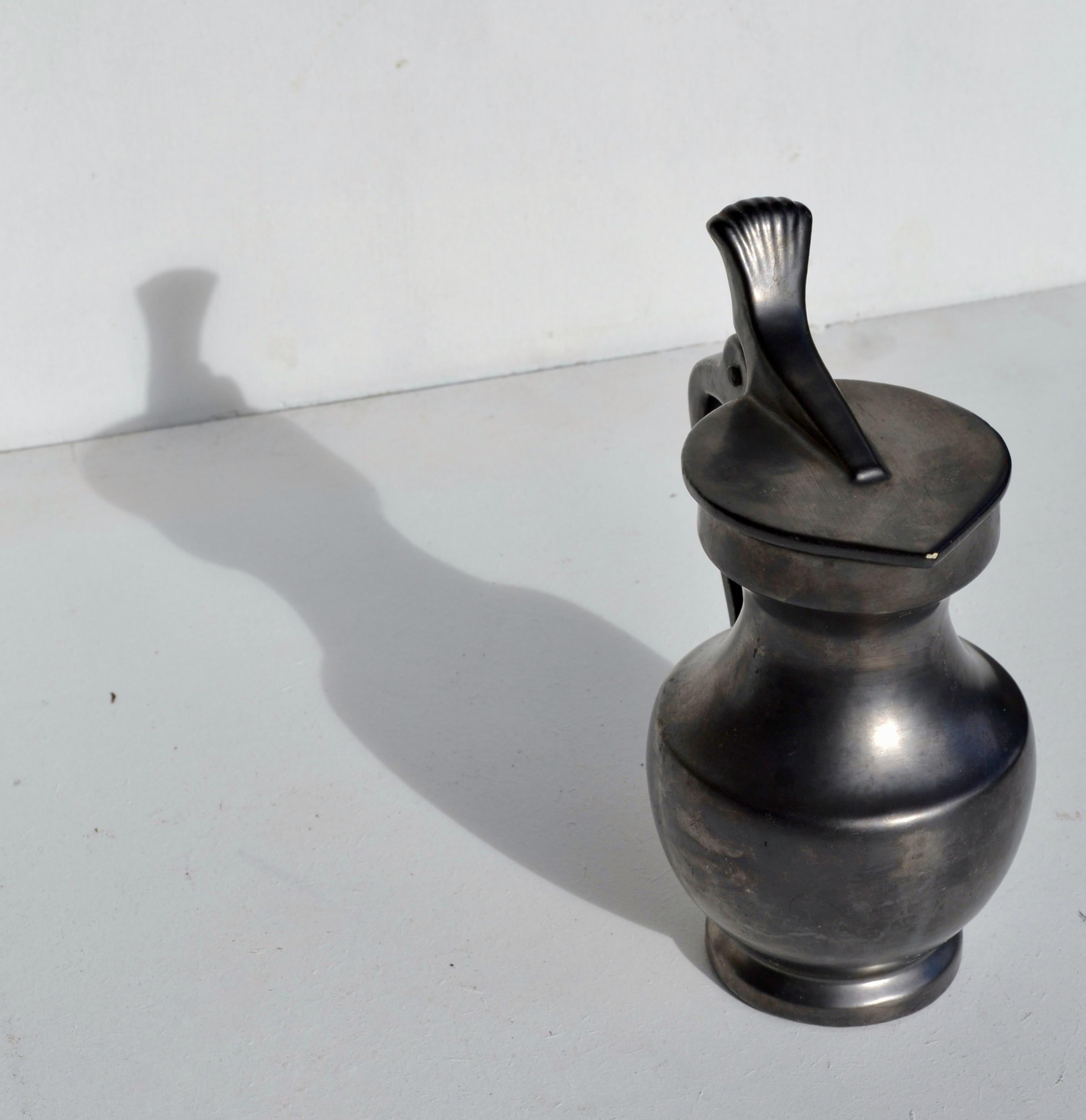 Una straordinaria brocca in ceramica francese del Mid-Century con smalto nero intenso, che unisce eleganza minimalista e design funzionale. La sua maniglia scultorea e il beccuccio dolcemente curvo creano un equilibrio armonioso tra forma e utilità,