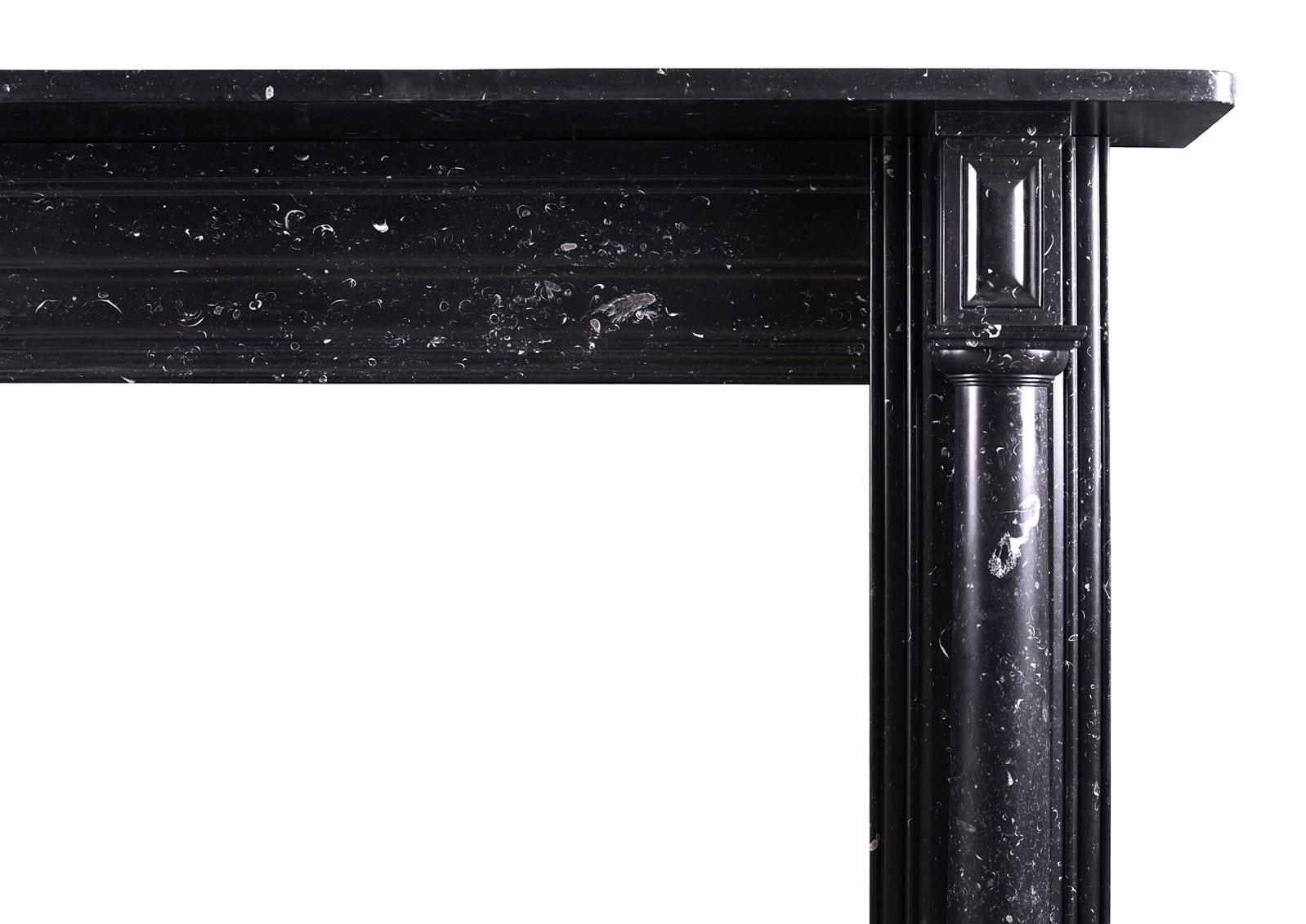 A Black Kilkenny marble Regency fireplace. The jambs with full columns surmounted by panelled end blockings. The reeded frieze with plain shelf above. English, circa 1820. Good quality black marble with characteristic fossils throughout.  

Shelf