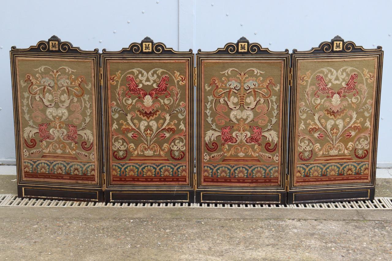 A black lacquered and gilt wood Victorian foldable fire screen
Composed of four panels, each one with Petit point tapestry upholstery, two of them decorated with stylized horses, the two others with lions.
Each panel surmounted by the monogram