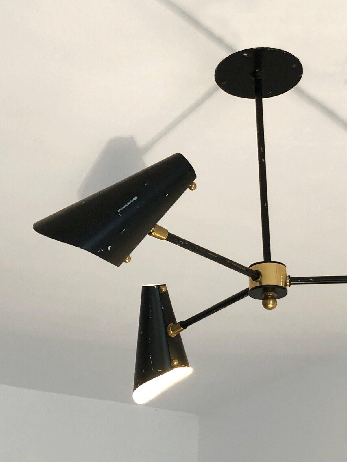 A pendant light with three arms of light, Modernist, Fifties, circular base in black lacquered metal, 3 arms of light with folded metal lampshades, golden brass finishes, to be attributed, France 1950.