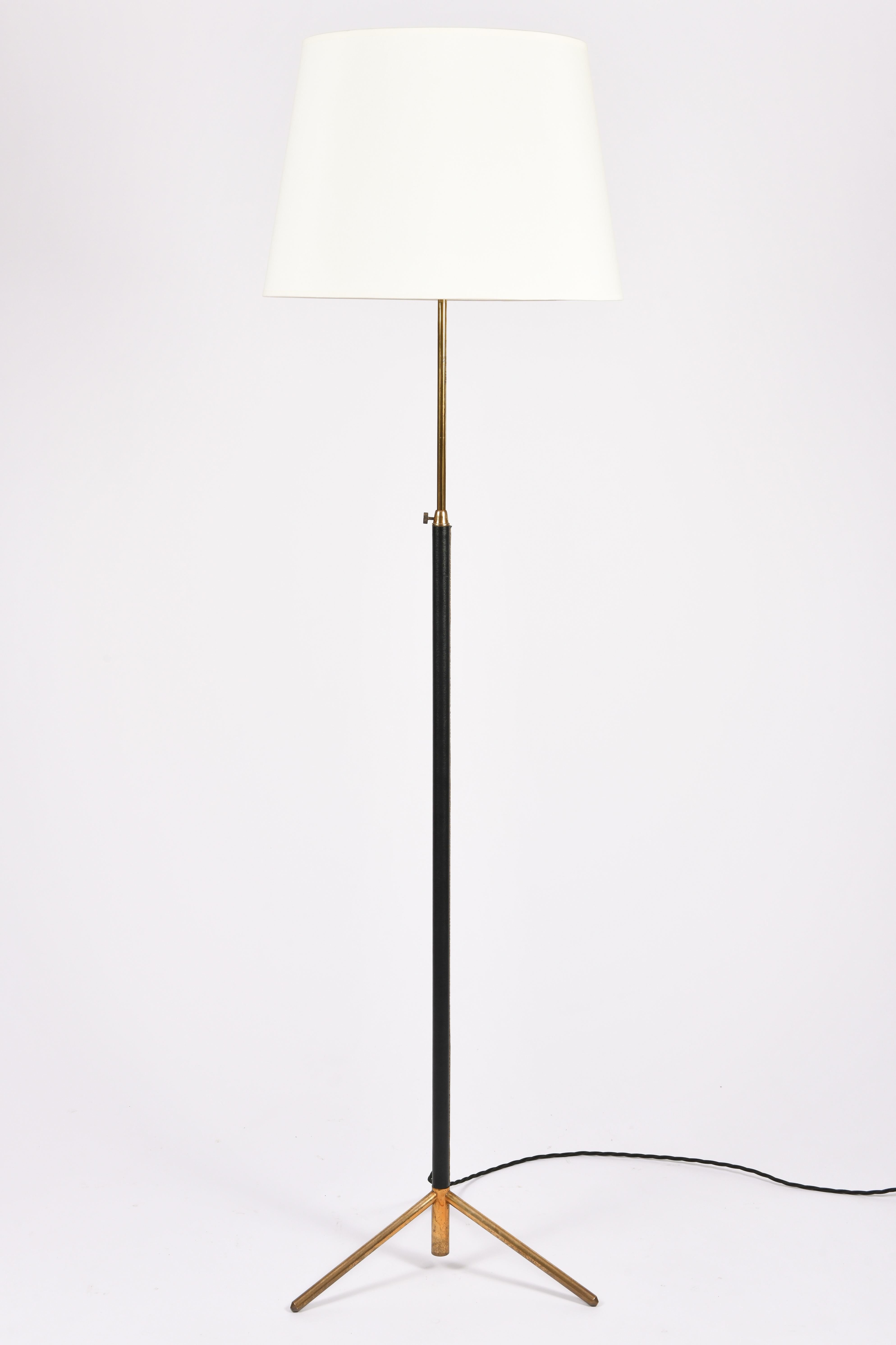 A saddle stitched black leather and brass tripod floor lamp, in the manner of Jacques Adnet
with a telescopic stem and a bespoke ivory fabric tapered shade
France, circa 1950.