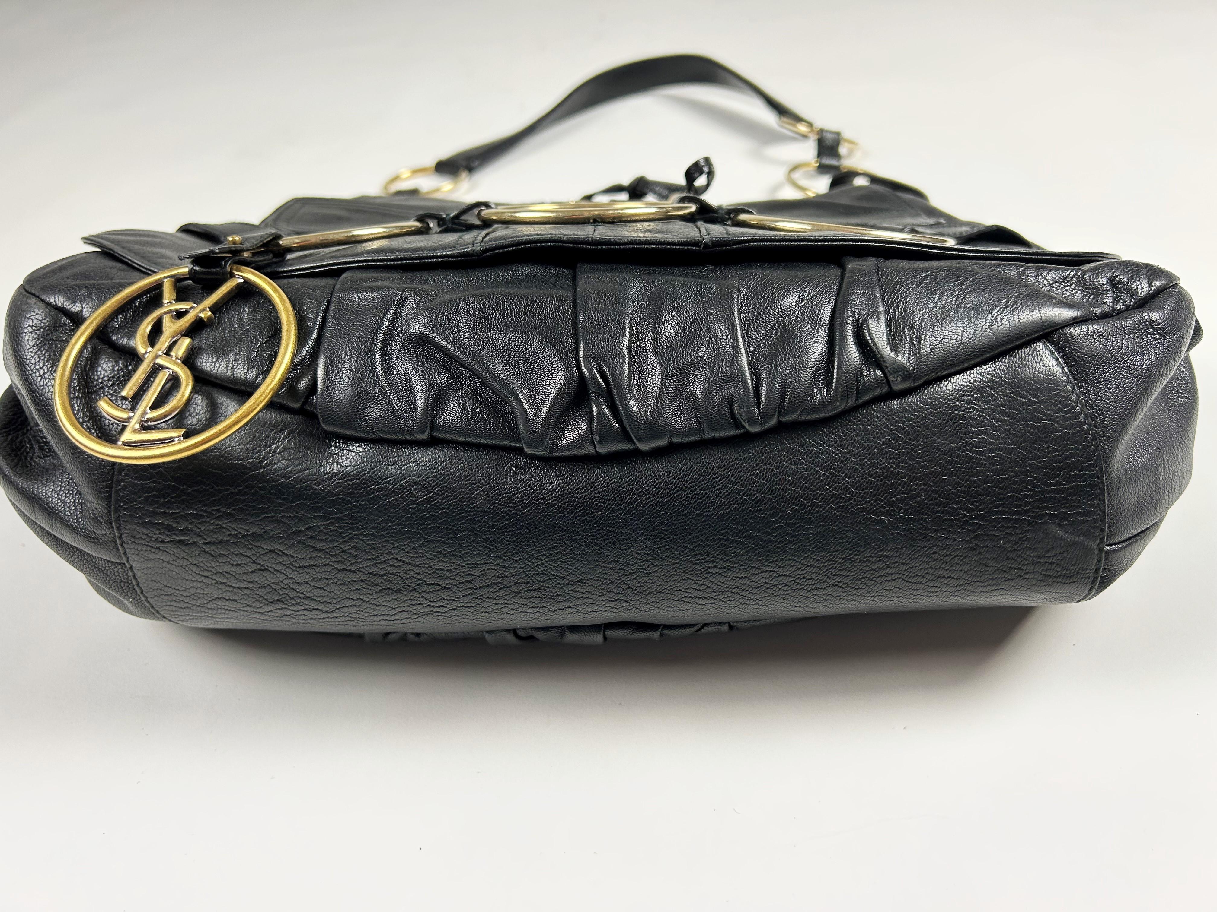 Circa 1980
France

Iconic black leather Saharienne bag signed Yves Saint Laurent Rive Gauche and dating from the 1980s. Besace shape with large flap with eyelets and crossed laces, two real patch pockets. Large golden brass rings, one with a large