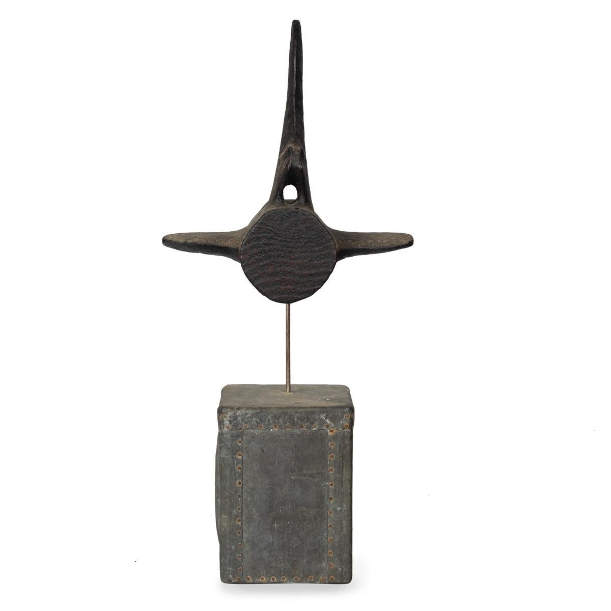 A black painted driftwood whale vertebra by Martin Scorey, set on a rectangular base made from a wooden form covered in nailed metal sheets, circa 2010.

