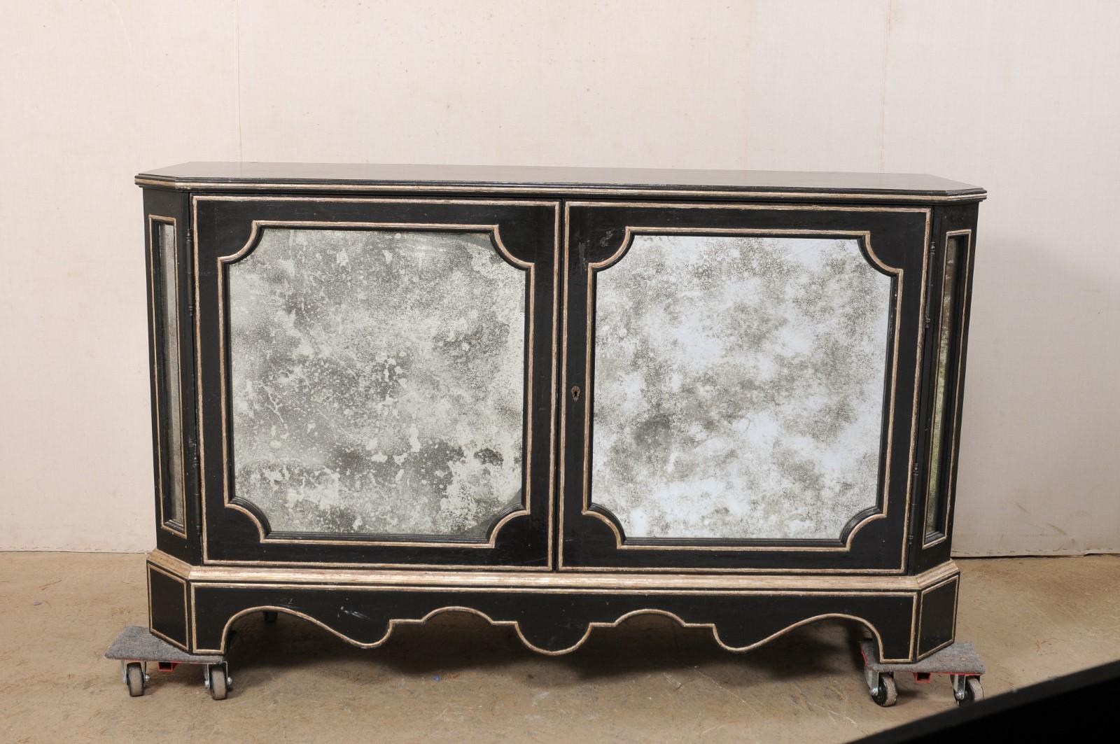 A vintage console cabinet with antiqued glass panels, by American creator/manufacturer Niermann Weeks. This stylish buffet is adorned in beautifully antiqued-mirror recessed panels about its exterior, has canted front side-posts, a nicely scalloped