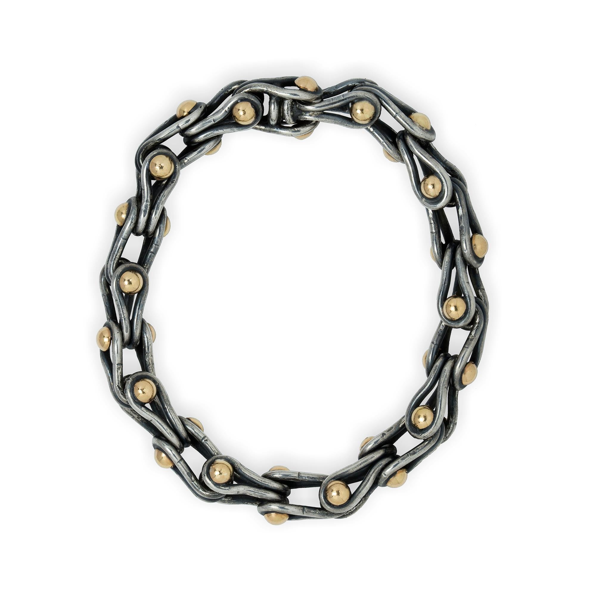 A black water ballet bracelet, the twenty U-shaped silver links in the form of a drop, each with two yellow gold hemispheres, handmade by Lucie Heskett-Brem the Gold Weaver of Lucerne, to a magnetic hidden clasp, hallamarked 18ct gold and sterling