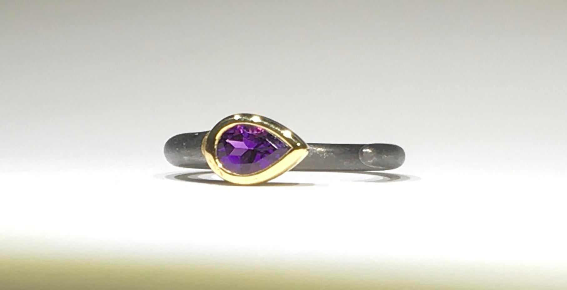 A Blackened Brushed Silver Ring with a Gold Plated Setting featuring a Pear Shaped Amethyst of 0.44 Carats. The 6.5 Gram Silver Band is a Size 7 USA and can easily be changed. 

Originally from San Diego, California, Kary Adam lived in the “Gem