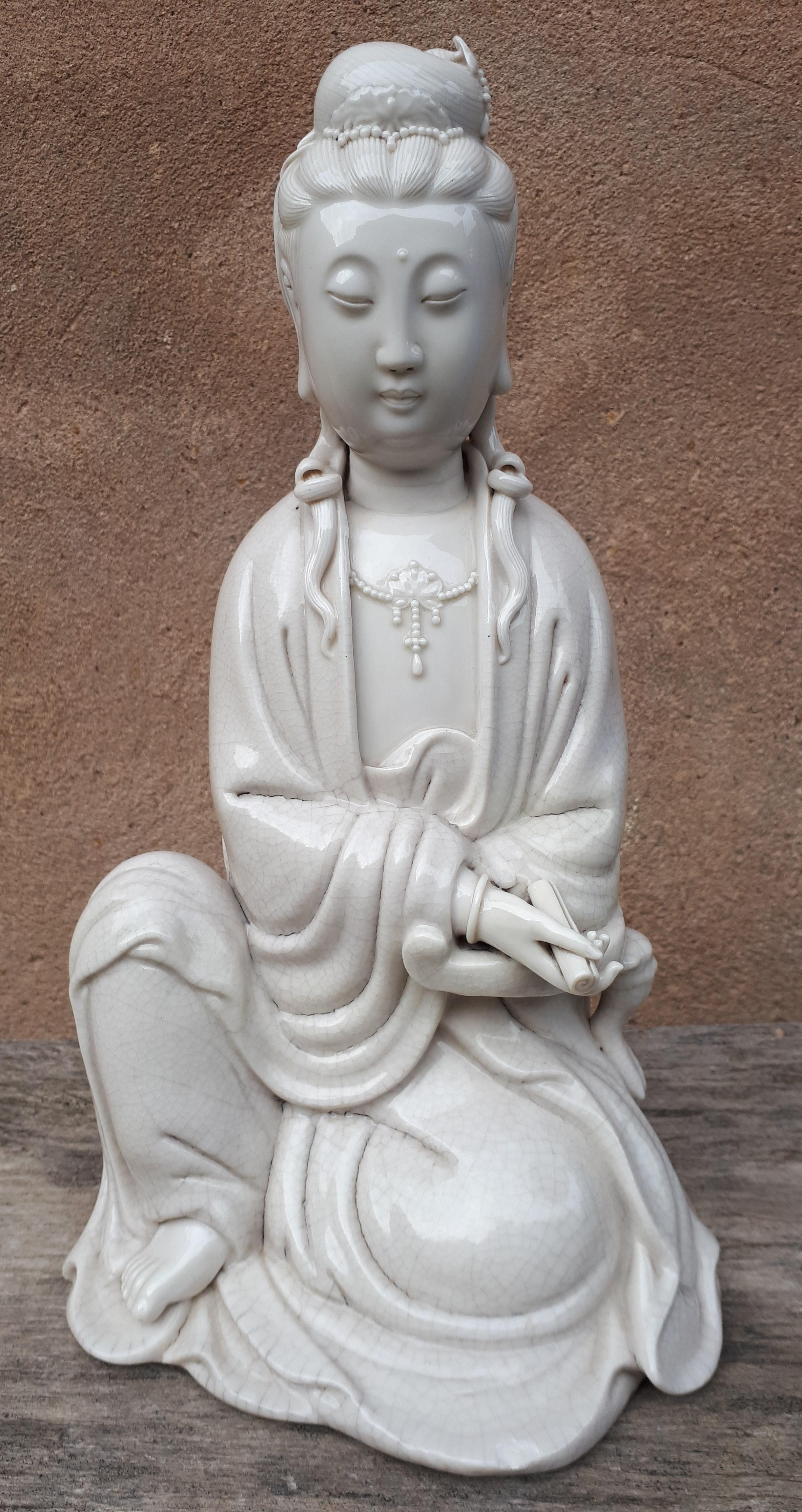 Statue of Guanyin in porcelain with clear glaze, represented in the position of royal relaxation.
Note the two different glaze, one cracked (for the clothes), the other not.
This figure is made by Su Xuejin (1869–1919), one of the most talented