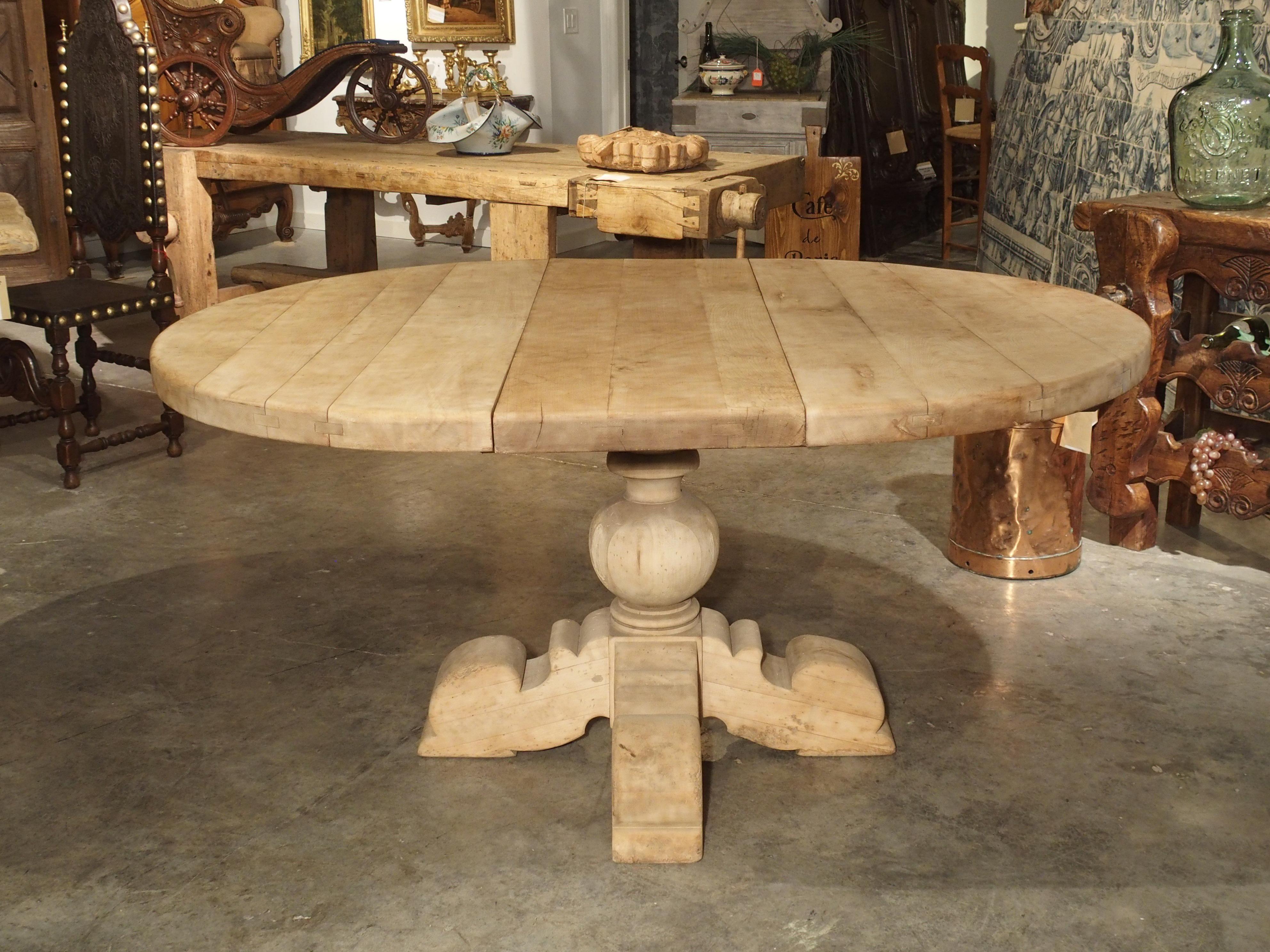 This interesting bleached table was produced in the early to mid-20th century in Belgium. The two-inch-thick top with mortise and Tenon construction is supported by an impressive and stout hand carved base. The columnar base is accentuated by a