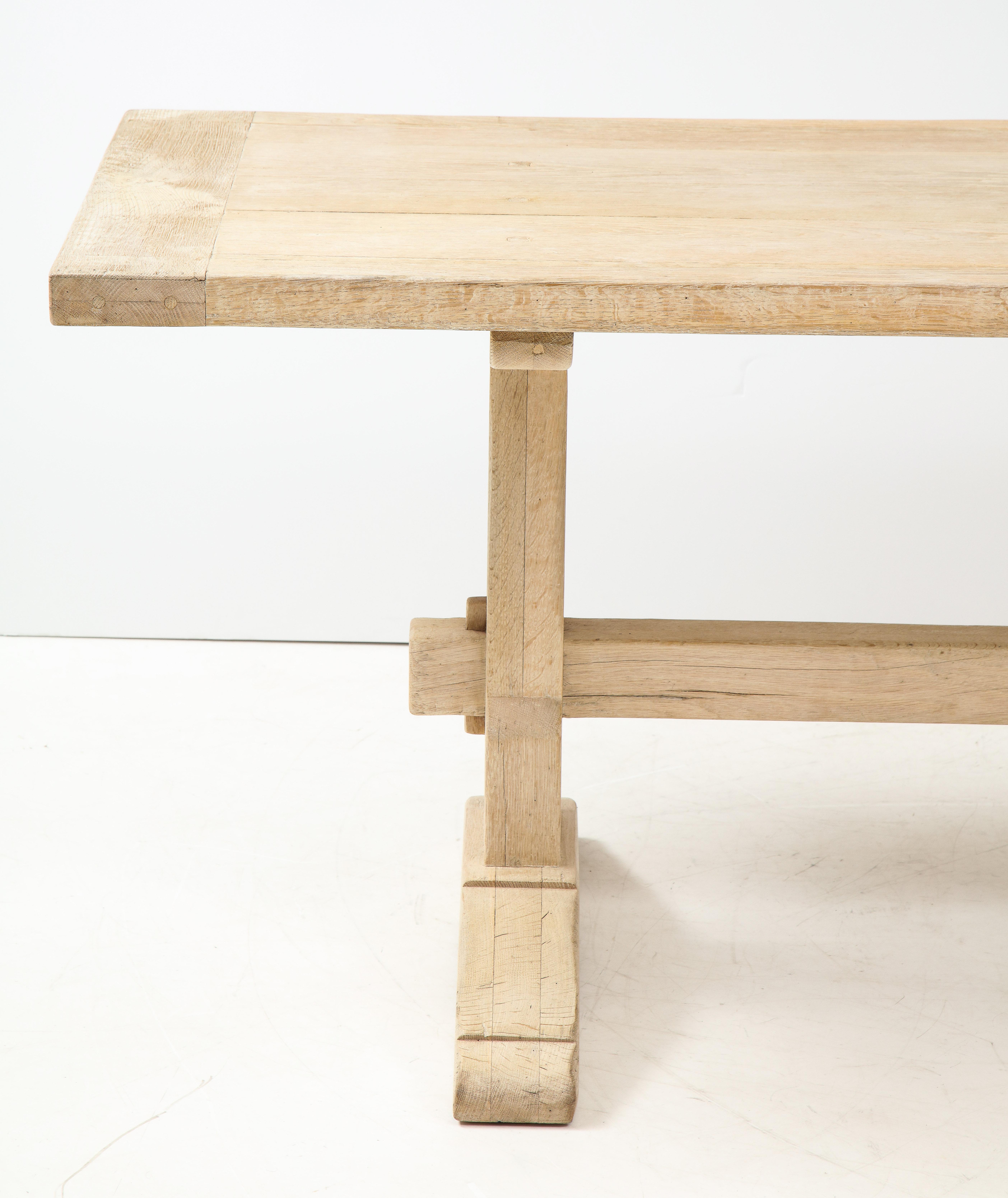 This long, narrow oak table with a trestle base has aged to a lovely patina. It can serve as a dining, kitchen or conference table. Although it is a traditional table, its light finish gives it a fresh, more contemporary look.