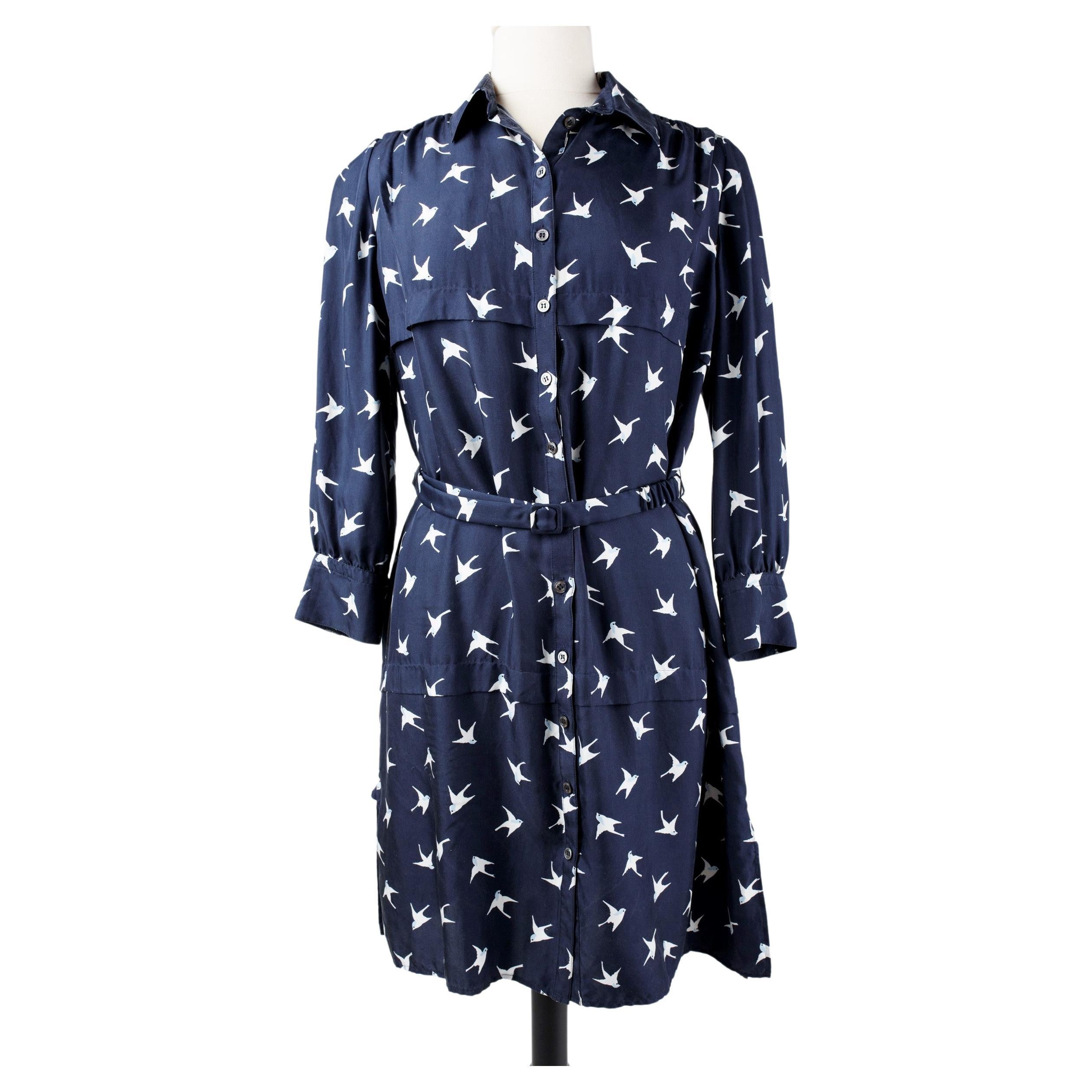 Circa 2000
France
Elegant and discreet blouse dress in navy silk twill printed with swallows by Nina Ricci.  Fluid dress with a belt at the waist and long three-quarter length sleeves with a little puff. Closed in the front by twelve pearly buttons