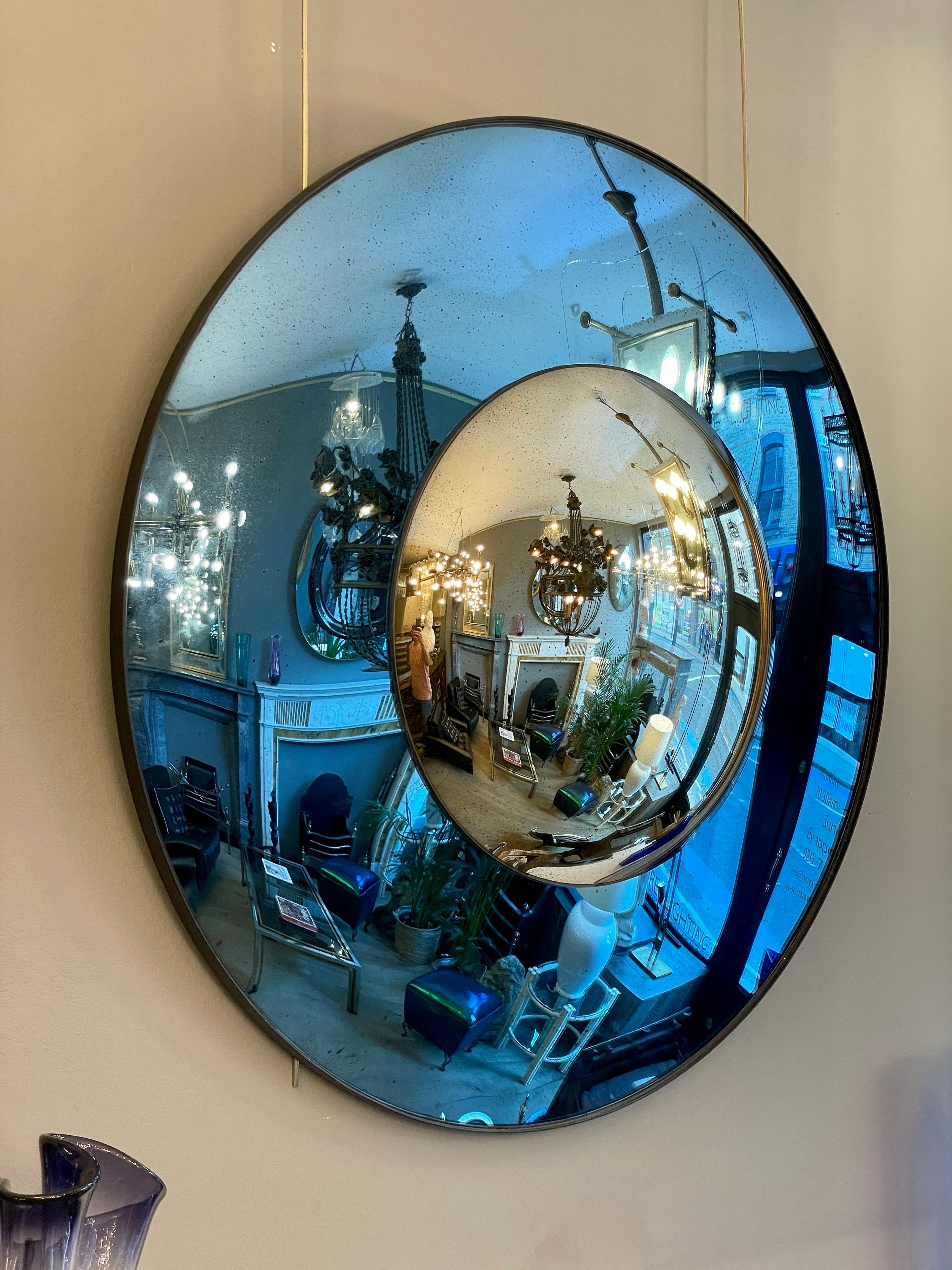 A circular convex mirror, with a distressed blue convex mirrored border with a silver distressed convex centre. Bronze finish banded frame.