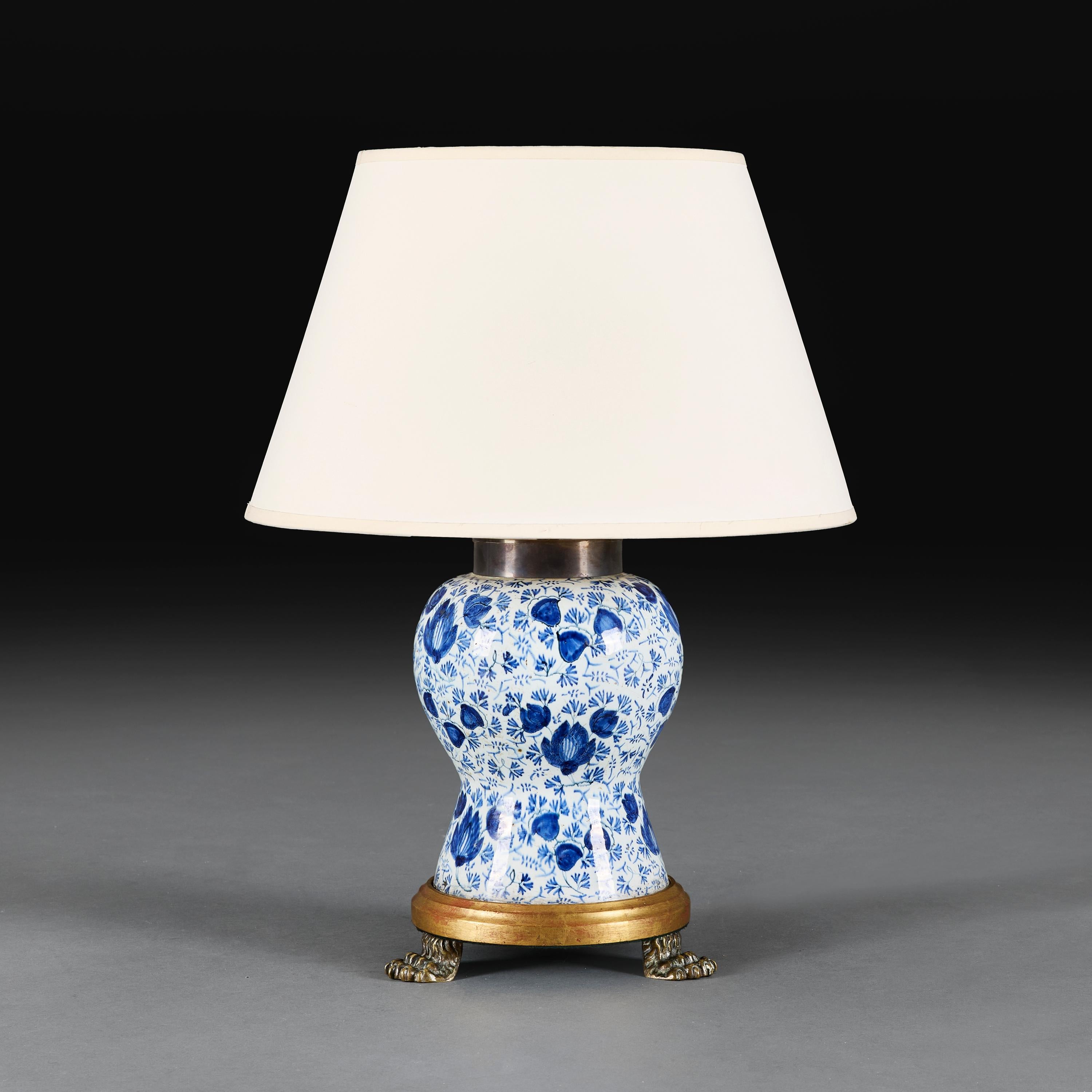 Países Bajos, hacia 1880.

Jarrón balaustre de delft de finales del siglo XIX con decoración foliada azul pintada a mano sobre fondo blanco, ahora montado como lámpara sobre una base de madera dorada con patas peludas de latón.

Altura 29,00