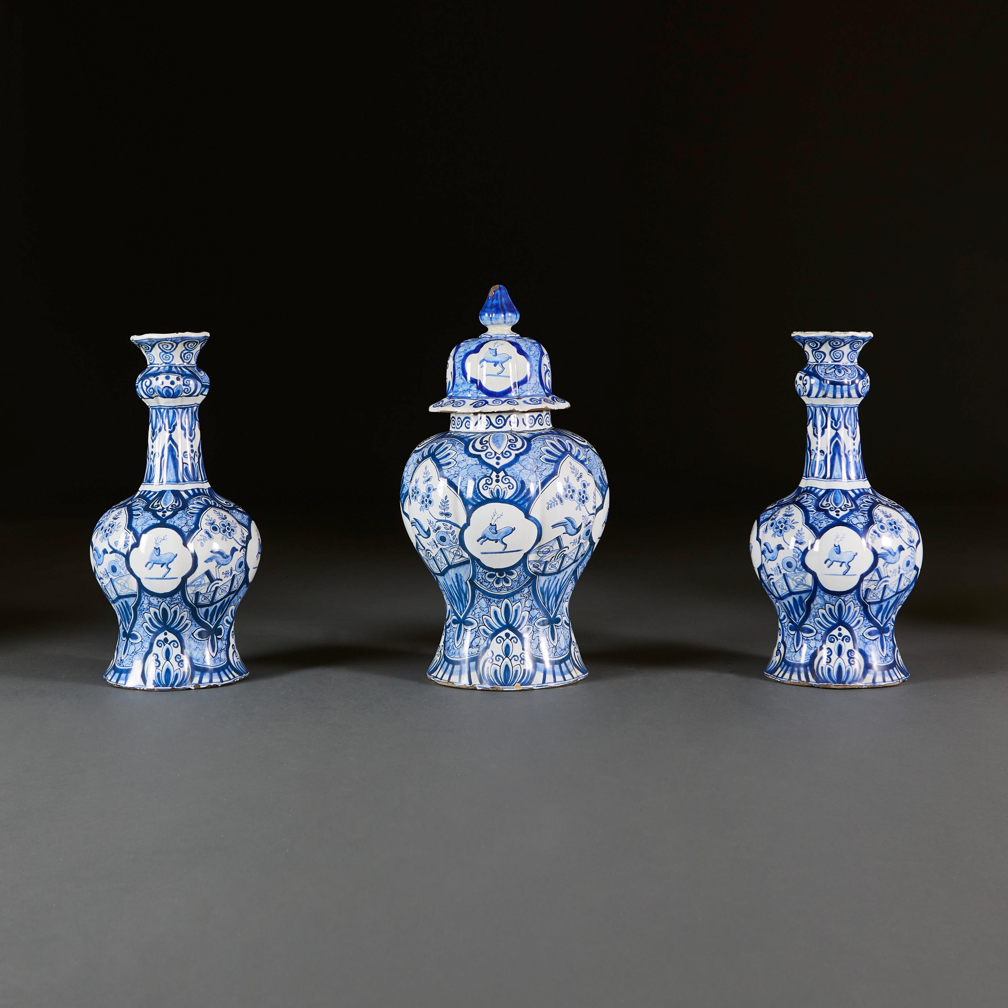 Low Countries, circa 1890.

A fine three piece garniture of blue and white Delft vases, comprising a large pot and cover, with two octagonal bottle vases with flared necks, each with cartouches showing leaping dear and oriental birds, with