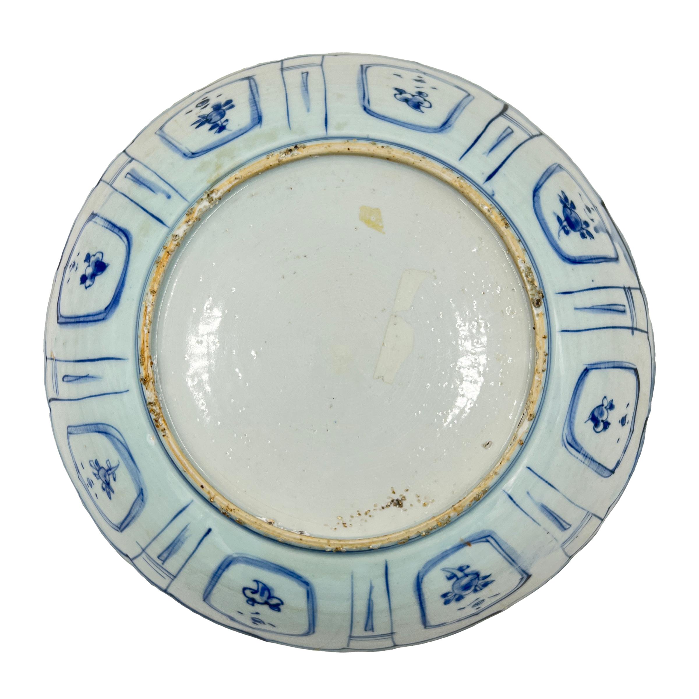 A fine blue and white kraak porcelain charger, The central cartouche with scalloped edge containing a scene of a bird surrounded by flowers and leafs, the border of the charger with eight panels containing birds and flowers separated by narrow
