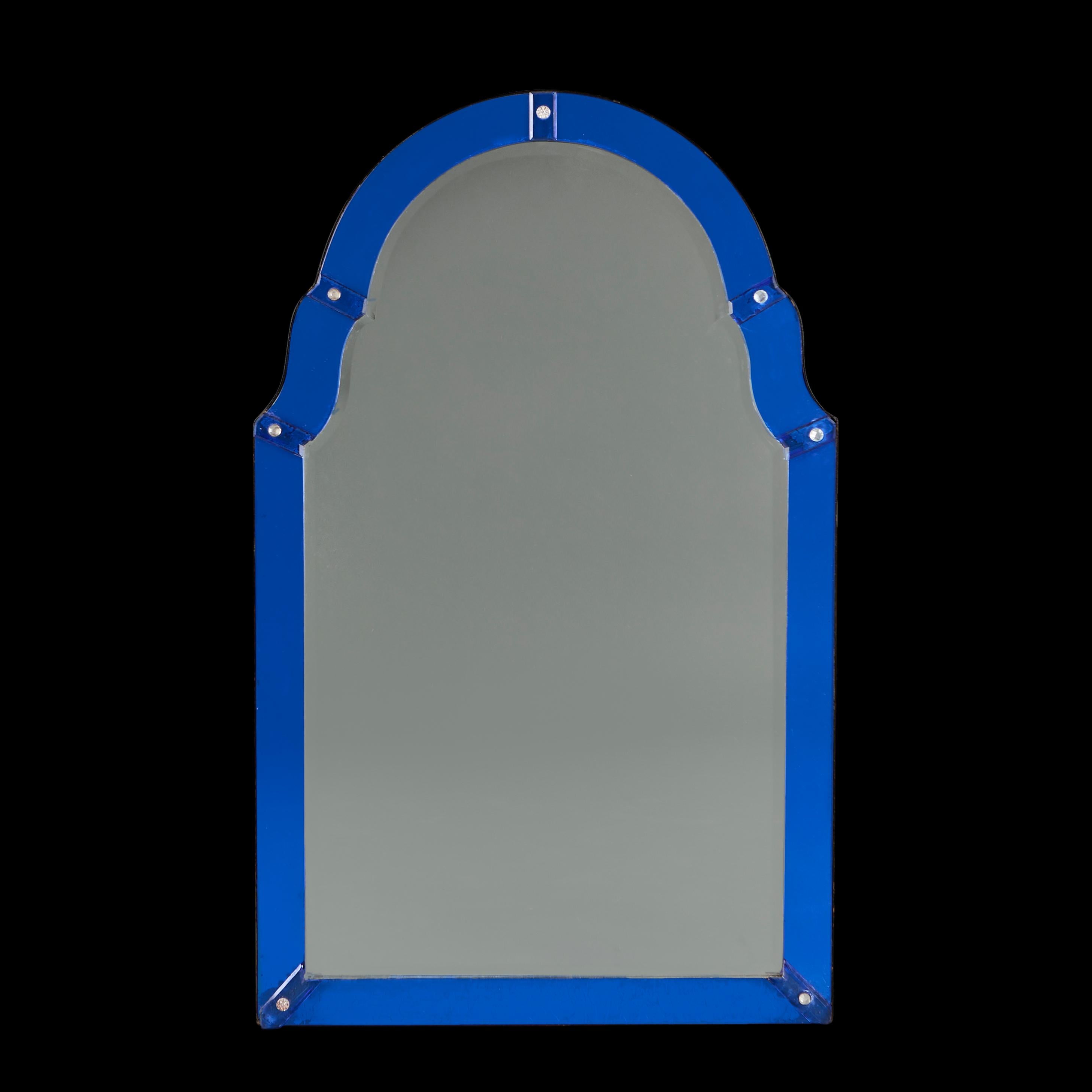 France, circa 1930
An Art Deco mirror with arched top, with blue glass borders, the segments secured with clear glass paterae to the corners. 

Height  88.0cm
Width   54.00cm