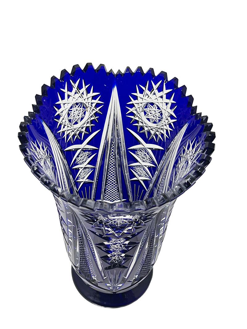 A Bohemian Blue cut to clear crystal vase, 1980s

A blue cut to clear crystal vase, raised on a round base. The vase is beautifully decorated with blue cut to clear crystal star shapes. The edge of the vase is scalloped with a shape of teeth (1