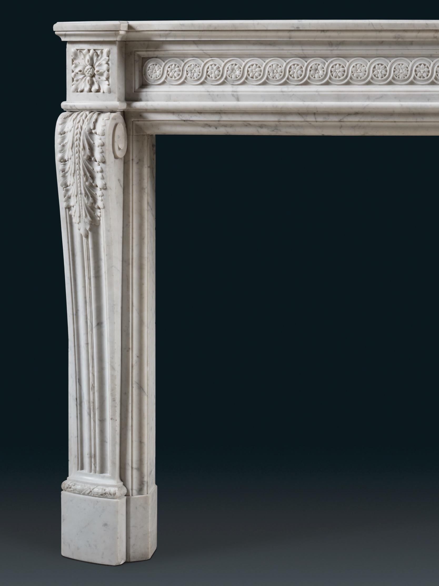 A striking 19th century chimneypiece carved in Carrara marble, with intricate carving. The piece demonstrates a frieze and shelf bowed in form with the shelf breaking forward over the corner blocks. The frieze has a lengthy stretch of running