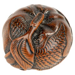 A boxwood netsuke depicting a mandarin with an engraved dragon, signed Tomomitsu