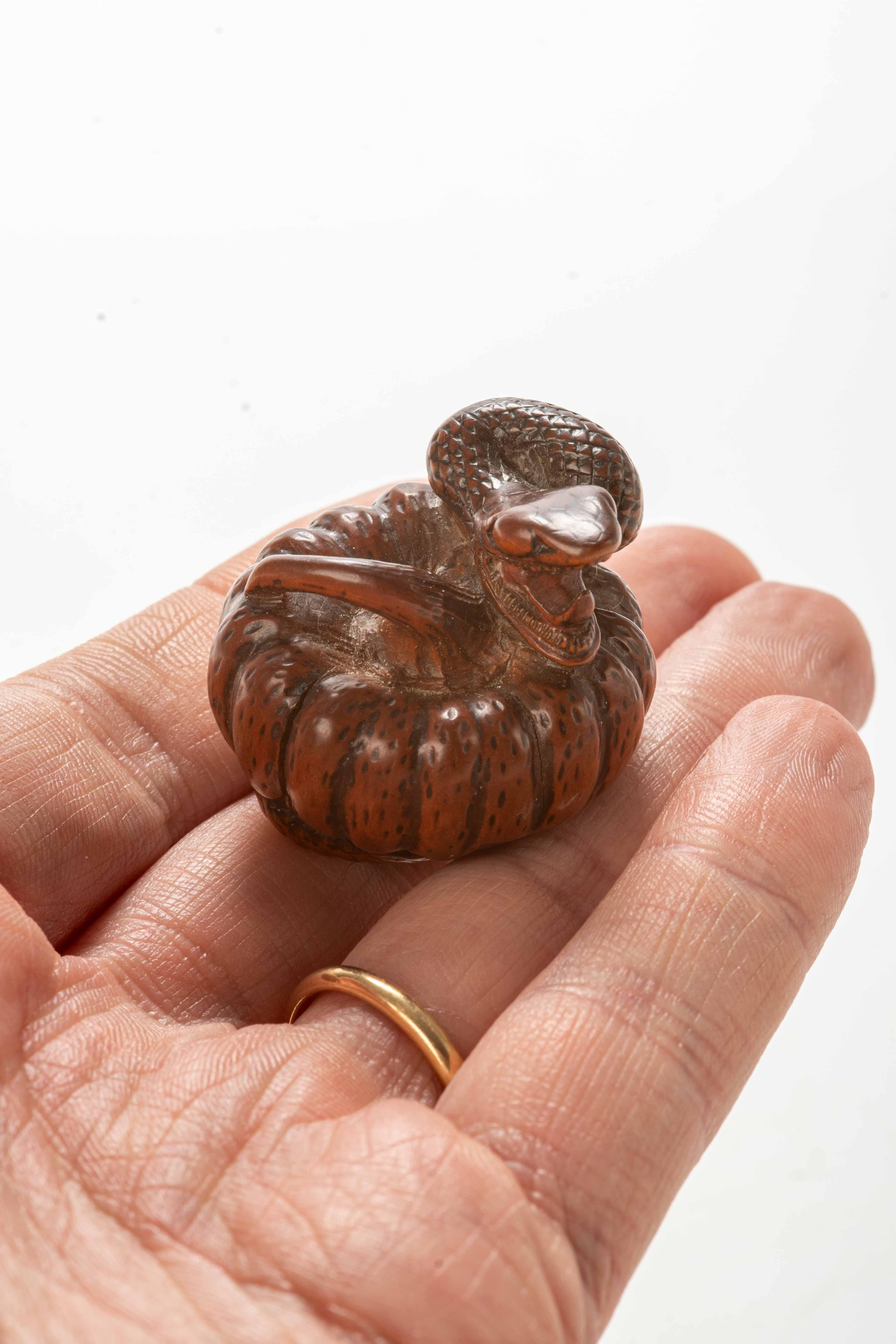 Sculpté Un netsuke en buis représentant un serpent enroulé autour d'un foulard en vente