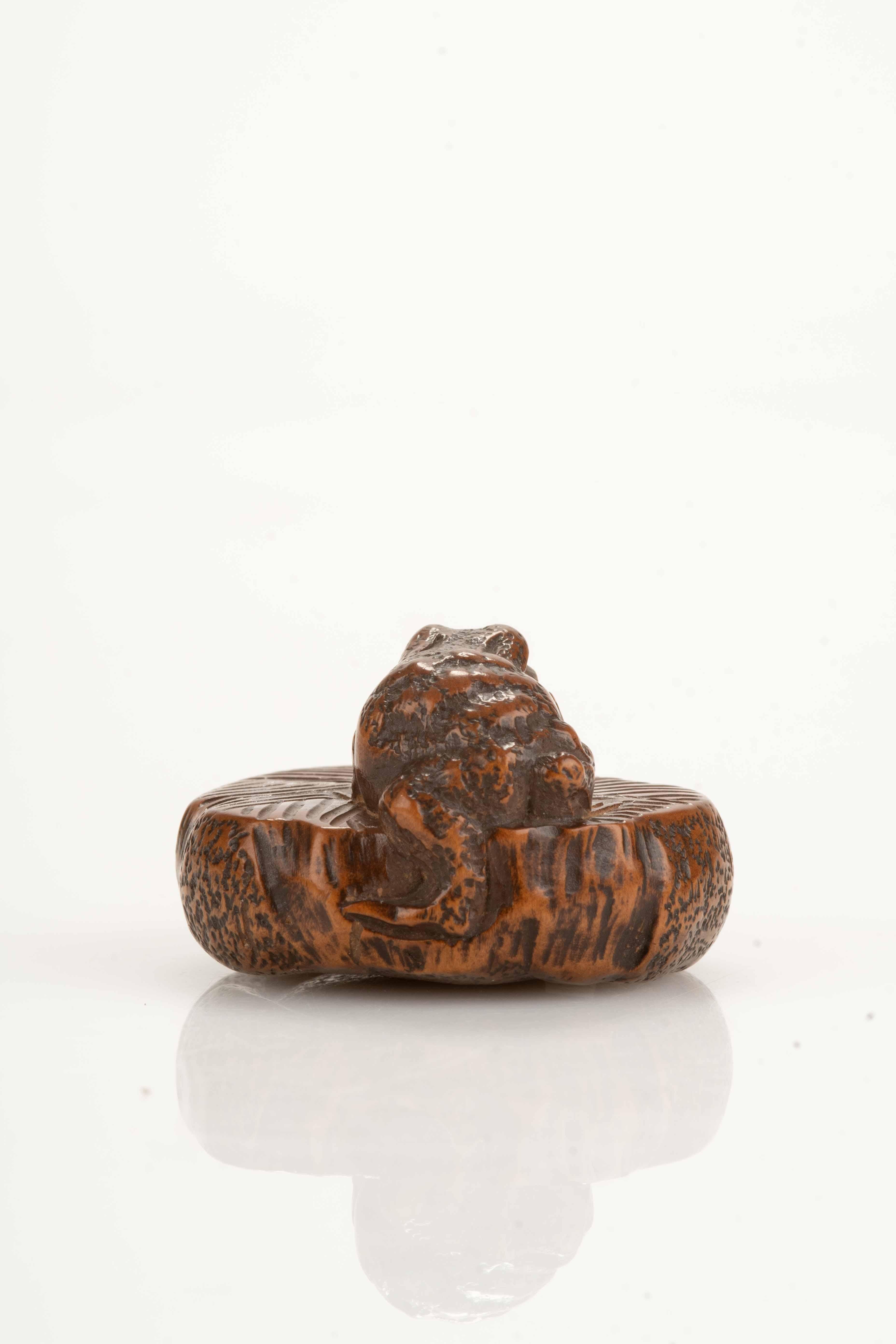 Japanese A boxwood netsuke depicting a toad on a circular stone millstone, signed Masanao For Sale