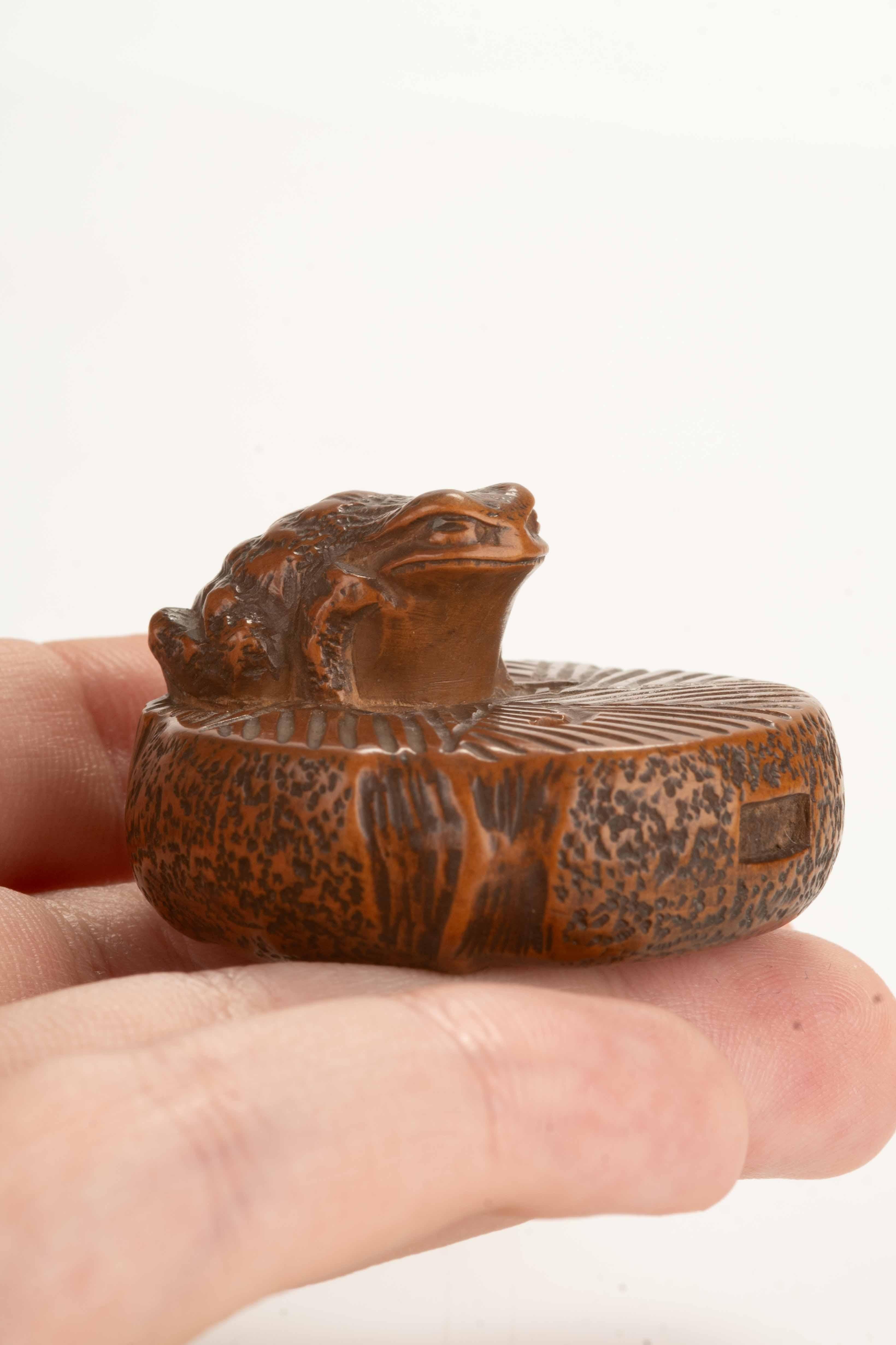 Hand-Carved A boxwood netsuke depicting a toad on a circular stone millstone, signed Masanao For Sale