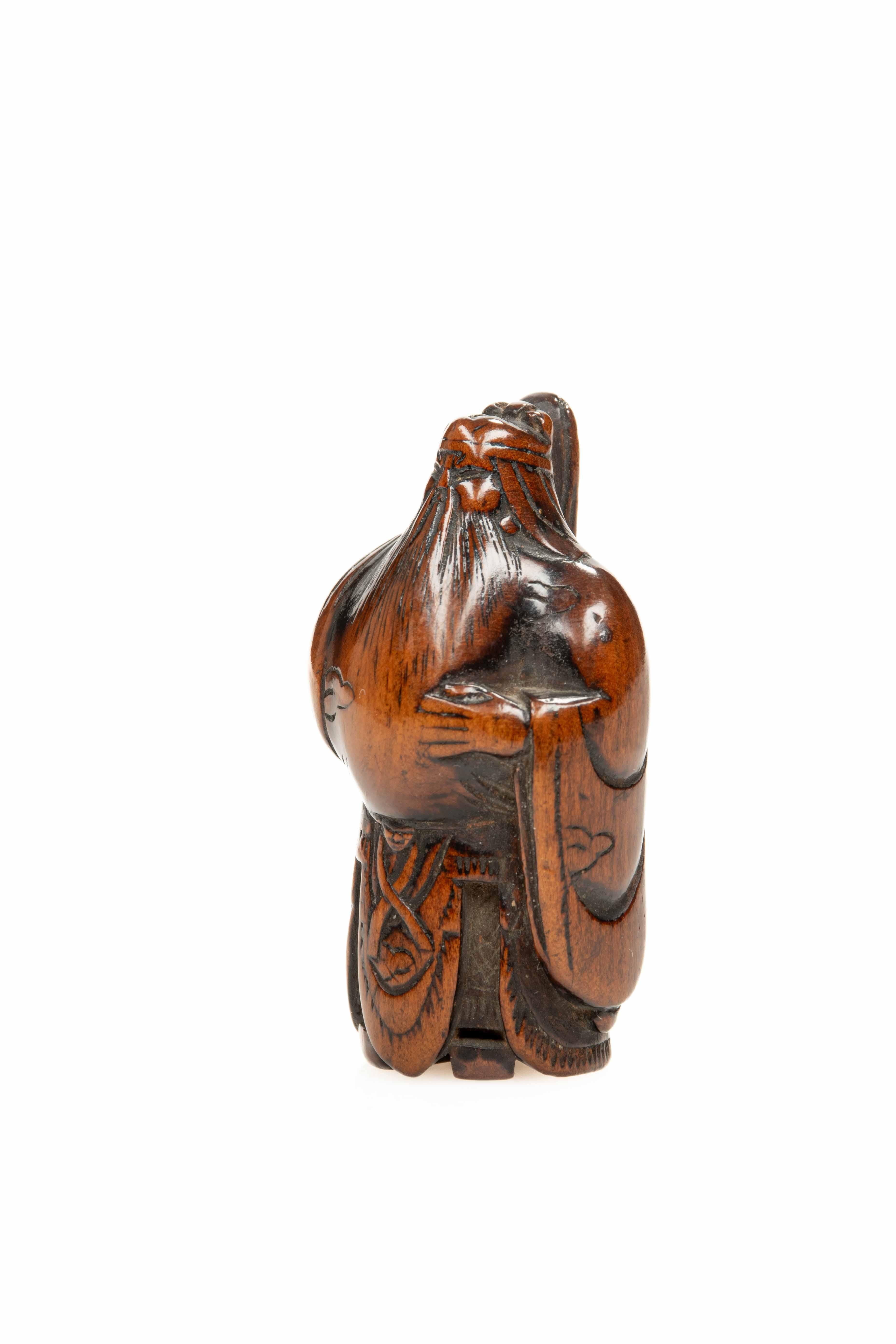 A boxwood netsuke depicting the Chinese general Guan Yu, shown standing and grasping his famous naginata, while his long beard falls down to his prominent belly.

Warm patina with excellent colour and sheen.

Himotoshi on the reverse, separated by