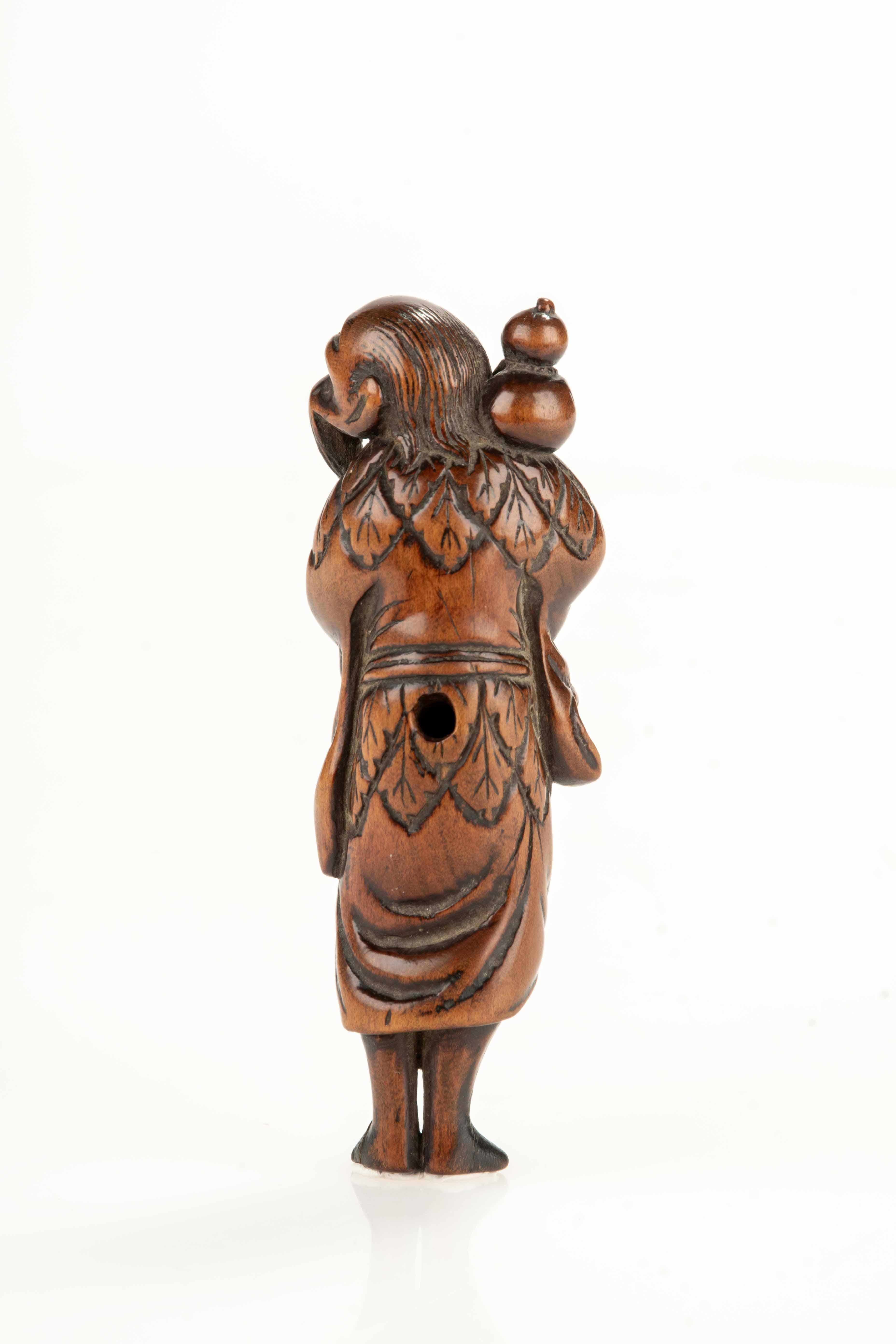 Un netsuke en buis à patine blonde, représentant un sennin à longue barbe marchant avec un bâton et une bouteille de saké.

Les vêtements sont finement sculptés avec des détails précis, tandis que les himotoshi sont placés dans le dos et sur le