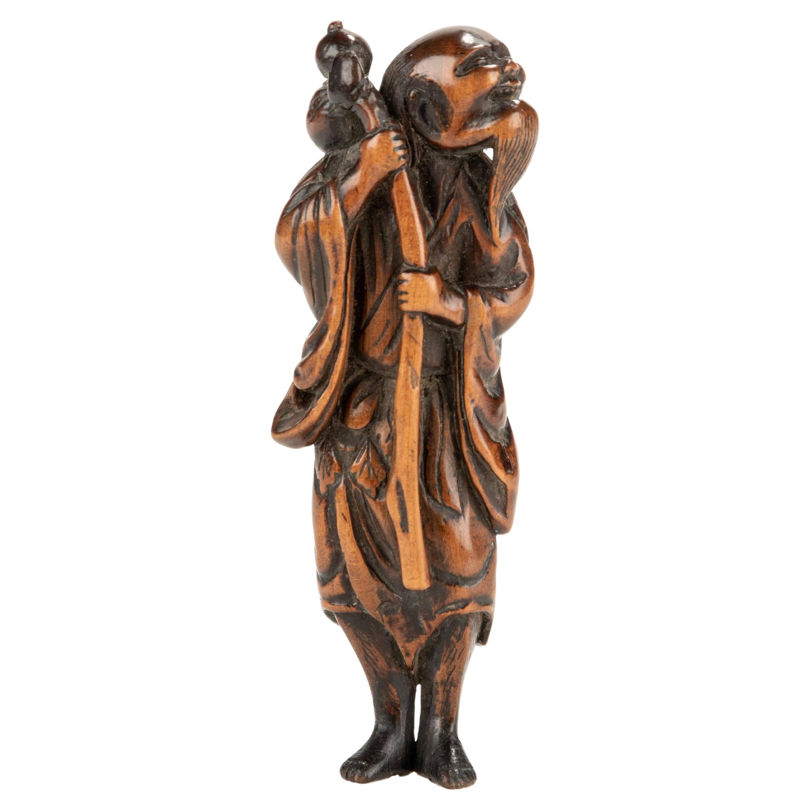 Netsuke en buis représentant un sennin avec une bouteille de saké