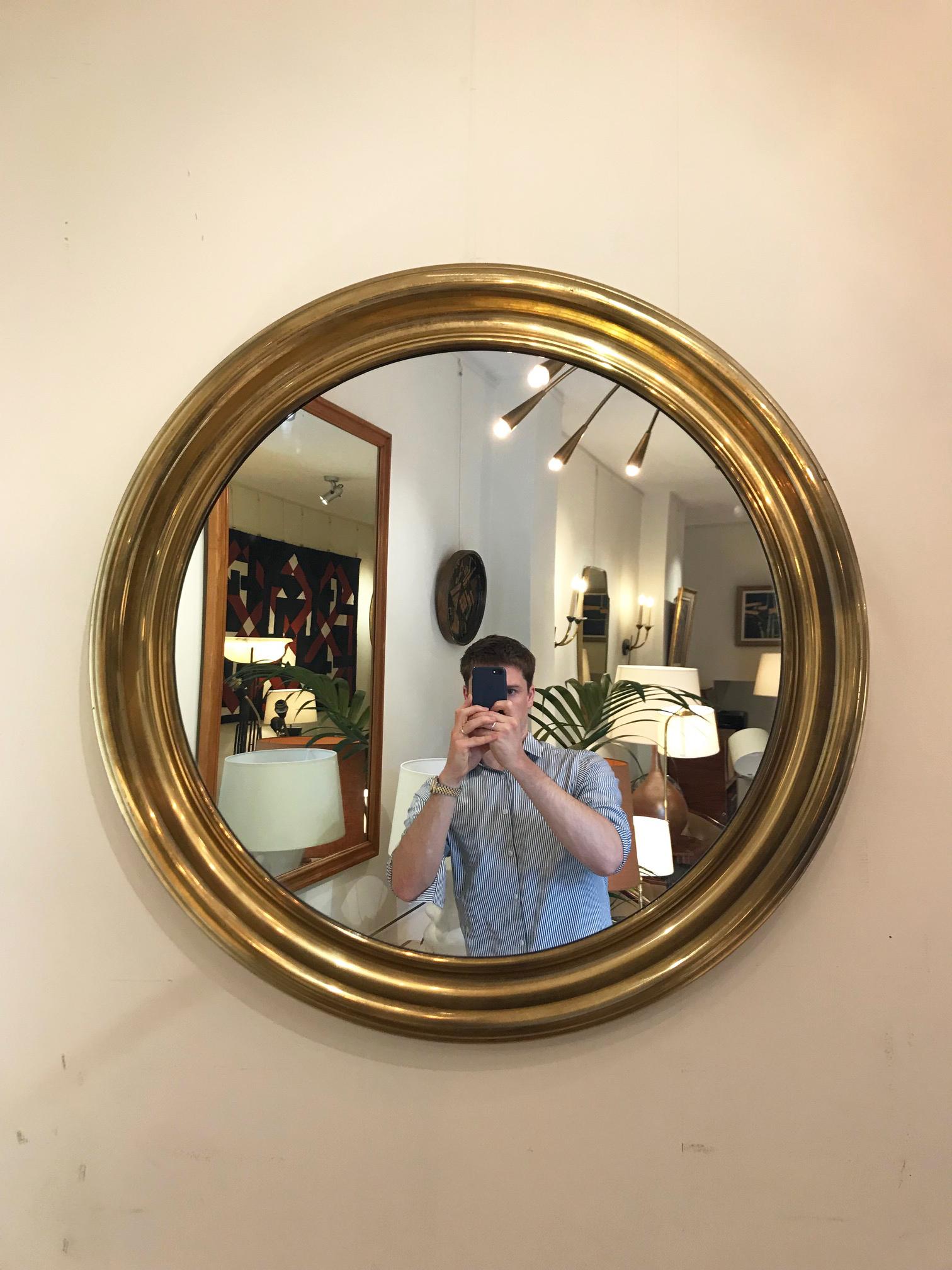 A brass circular mirror, with a wide moulded frame
France, circa 1950.