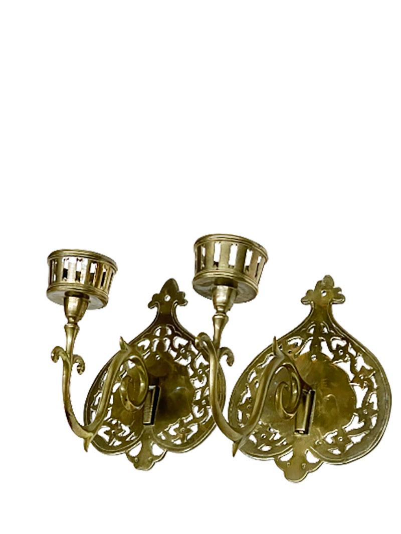 A brass 19th century wall candle holders

A brass 19th century wall candle holders with a single arm. 
A candle holder with a round openwork tray with c volutes arms. 
The arm is hung by hook

The candlesticks have signs of wear. These can be