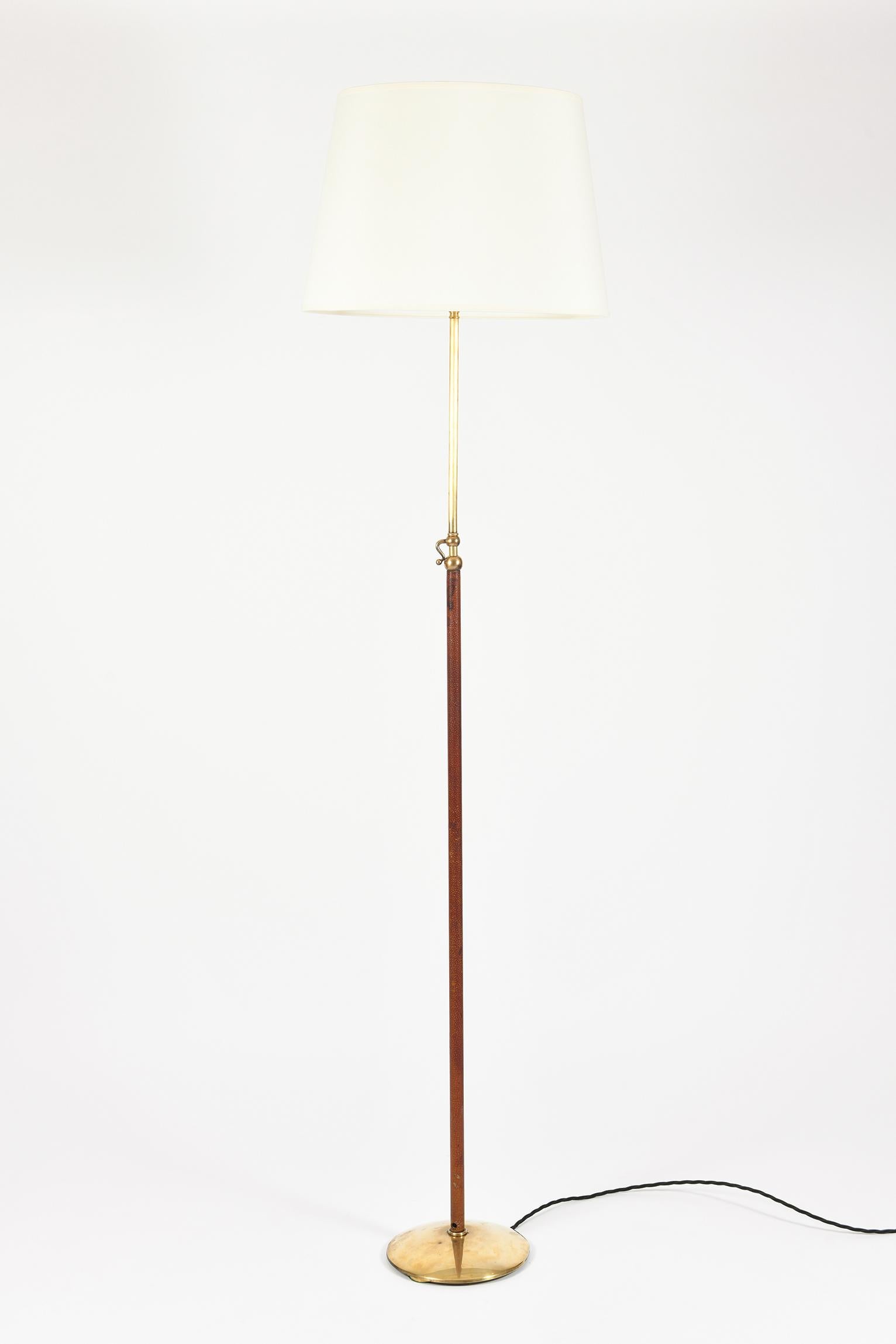 A telescopic brass and saddle stitched brown leather floor lamp, in the manner of Jacques Adnet
France, circa 1950
The stated dimensions include the shade and the set height as shown on the photos, and can be much taller when extending the